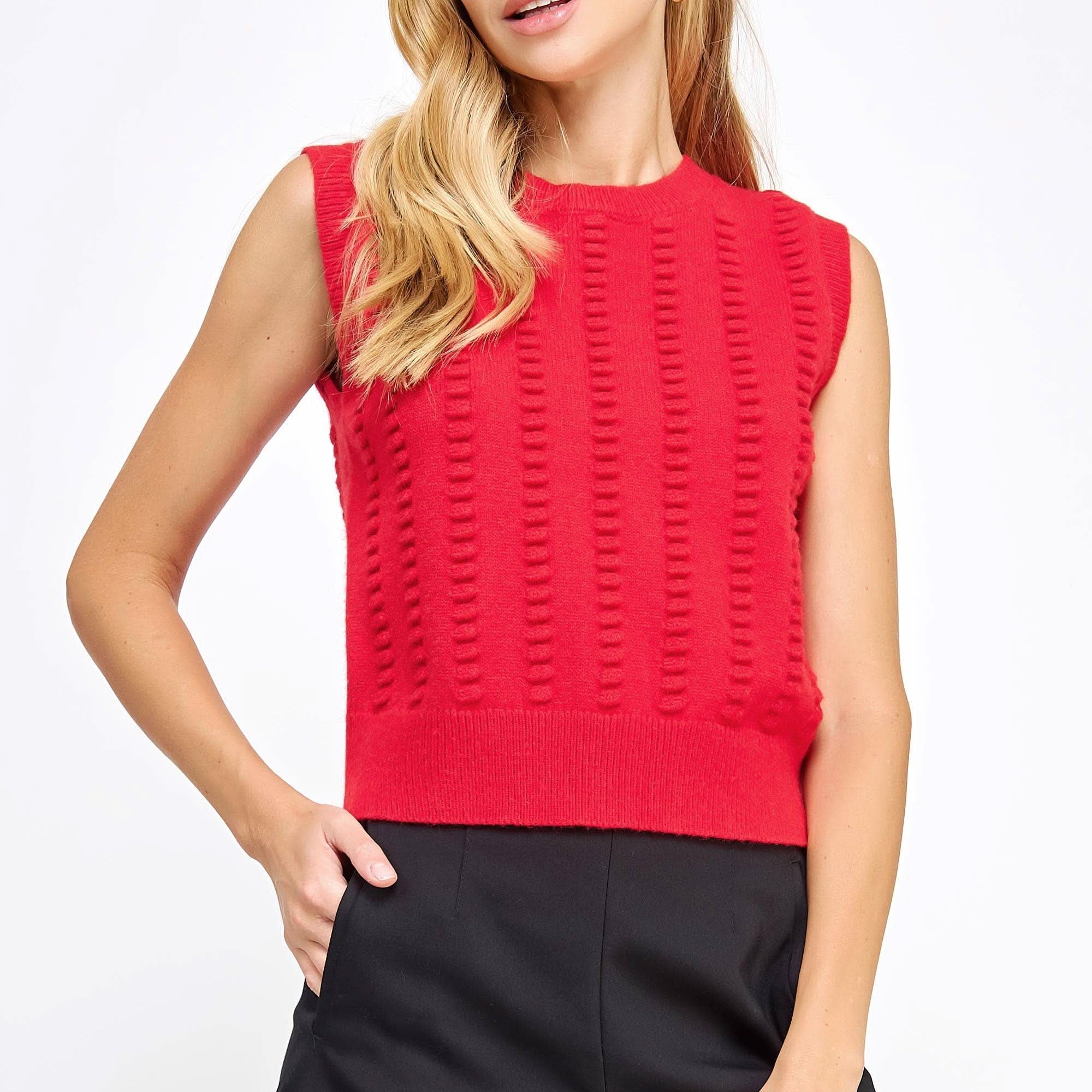 Woman wearing red textured sweater vest with black shorts