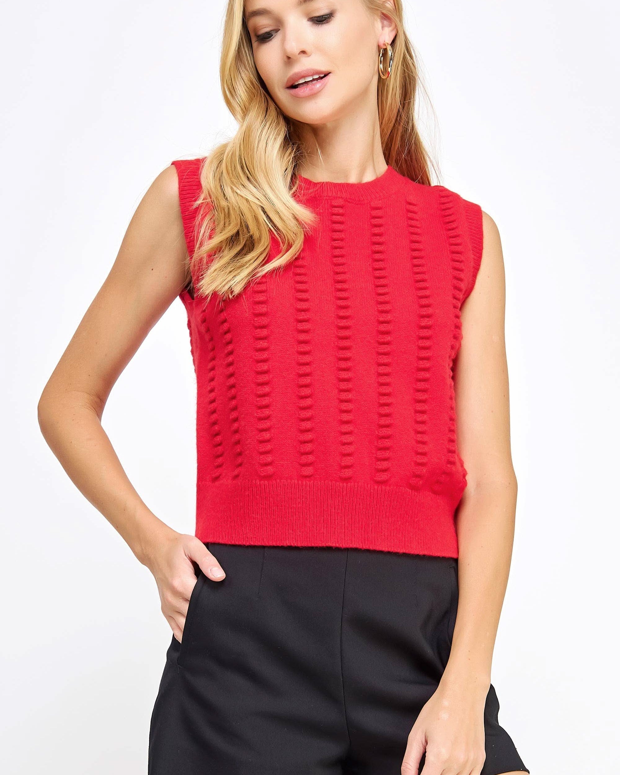 Woman wearing red textured sweater vest with black shorts