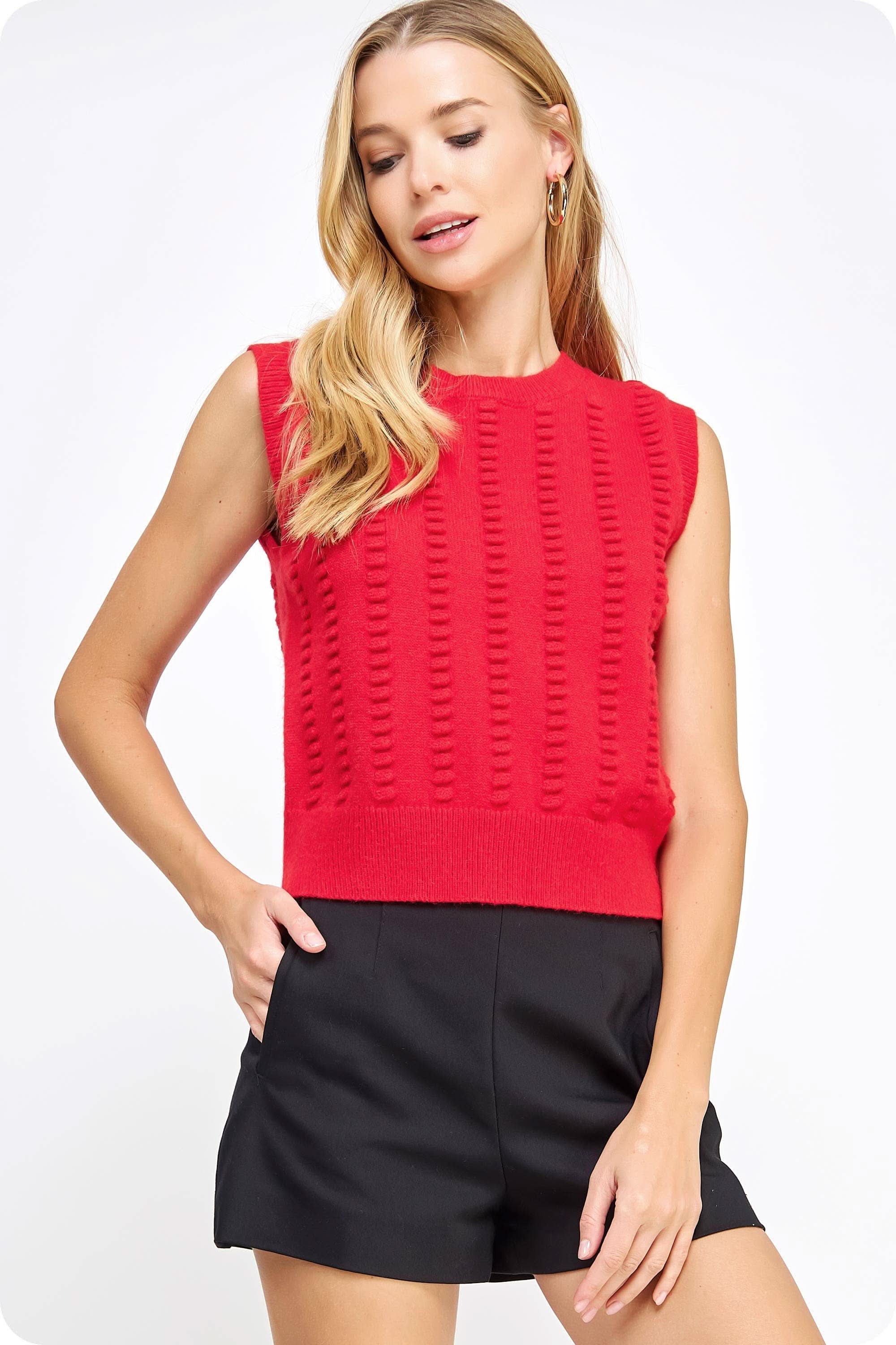 Woman wearing red textured sweater vest with black shorts