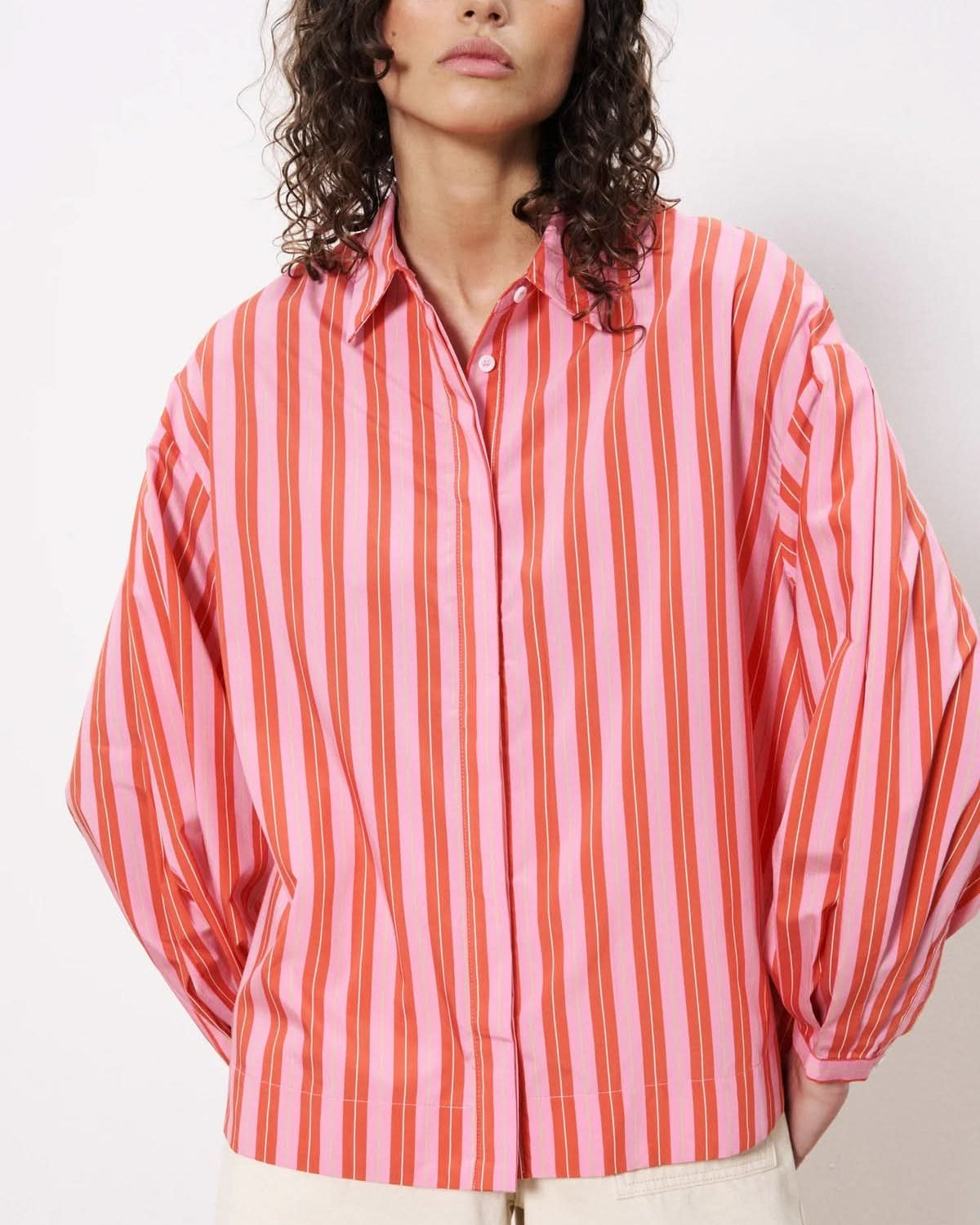 Woman wearing long sleeve button down satin blouse with red and pink stripes
