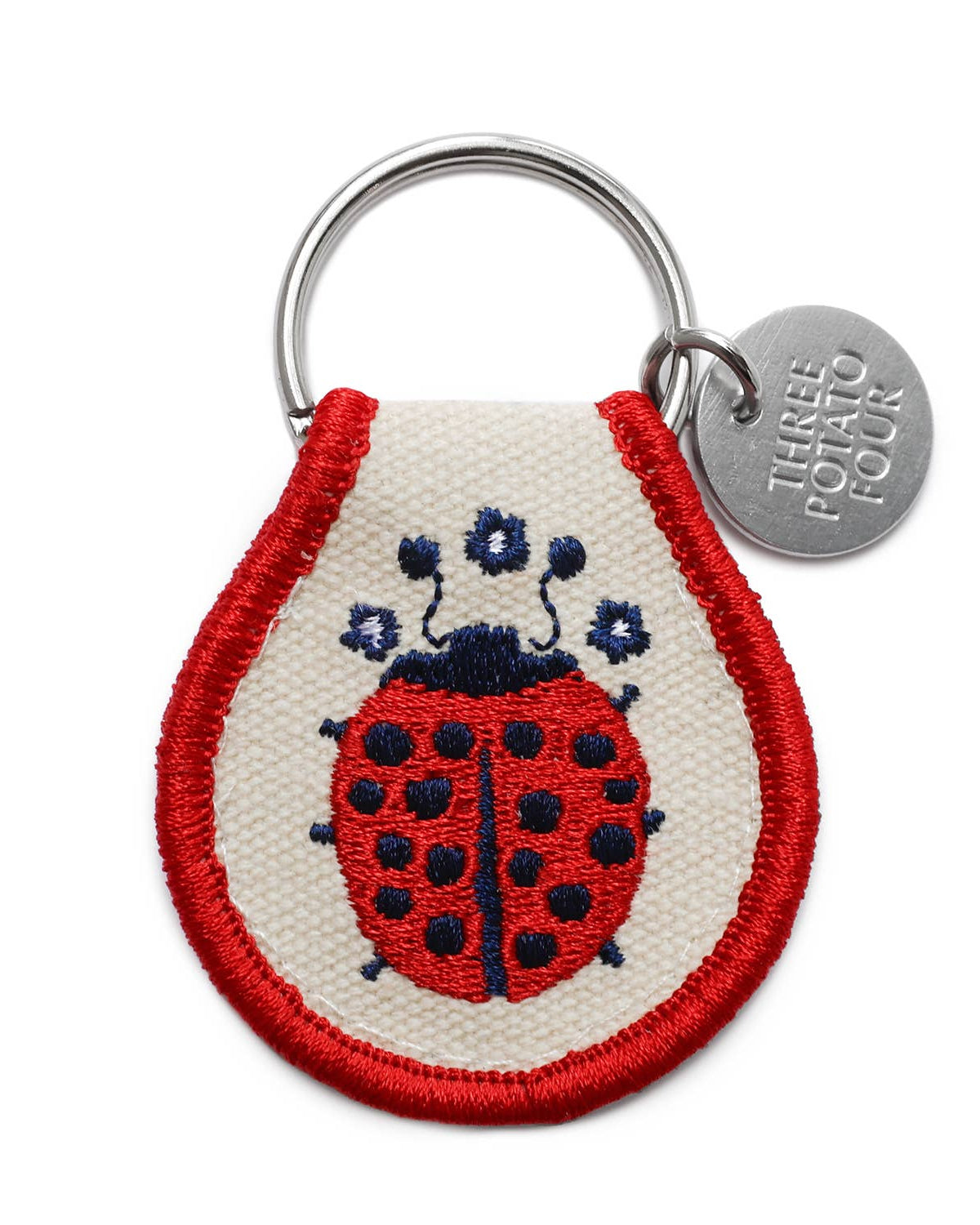Keychain with a ladybug design and 'Three Potato Four' tag on a white background