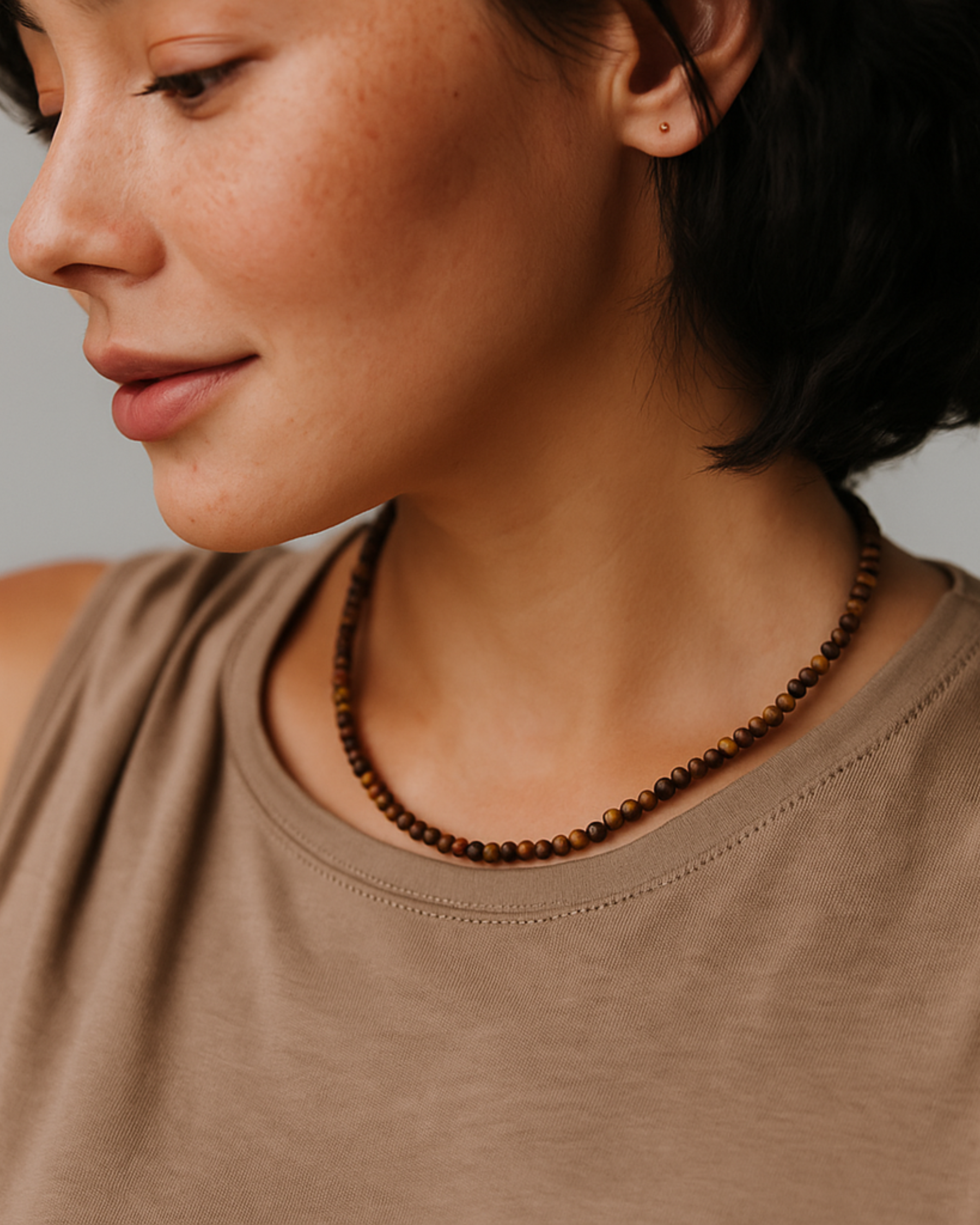 Woman wearing a brown beaded necklace against a neutral background