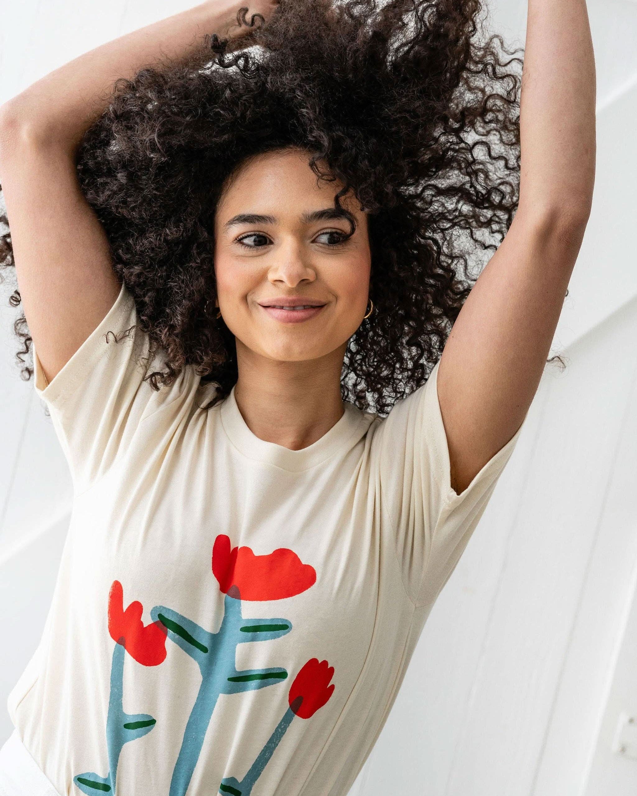 Woman smiling wearing Cream white Tshirt tee with three red tulip doodles on the Tshirt
