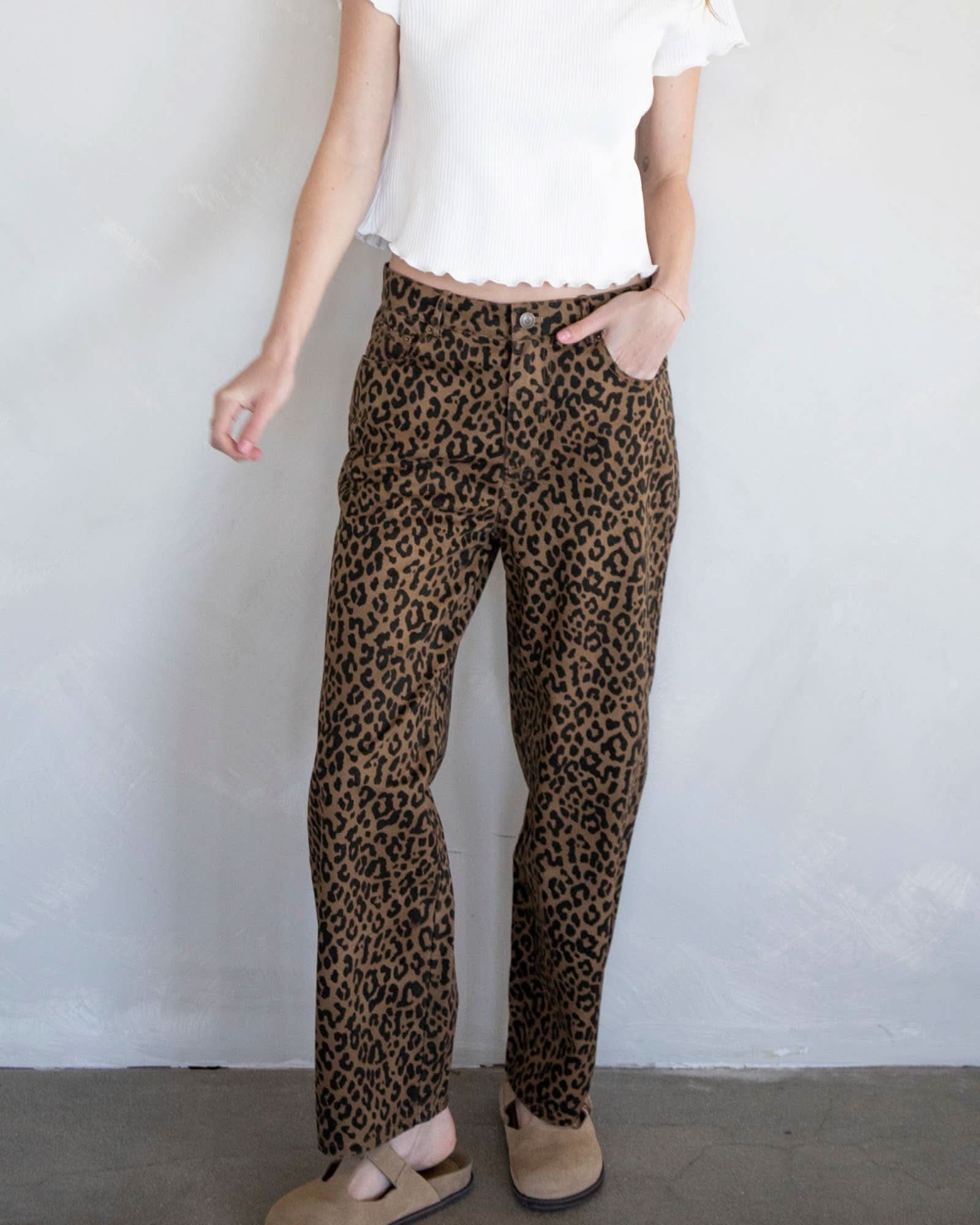 Person wearing leopard jeans standing against a white background