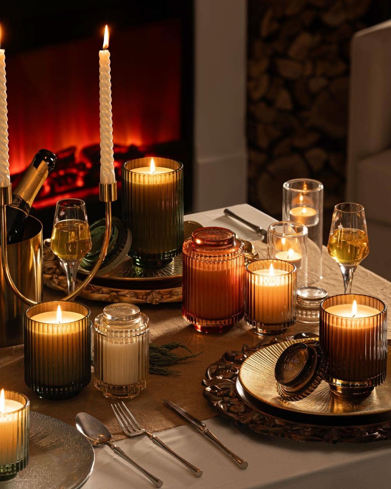 Dining table set with candles and glasses in front of a fireplace