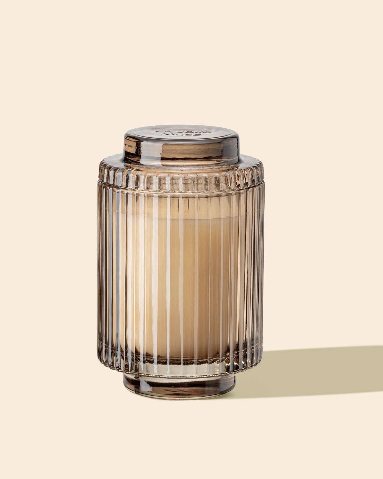 Decorative glass jar with a candle inside on a beige background