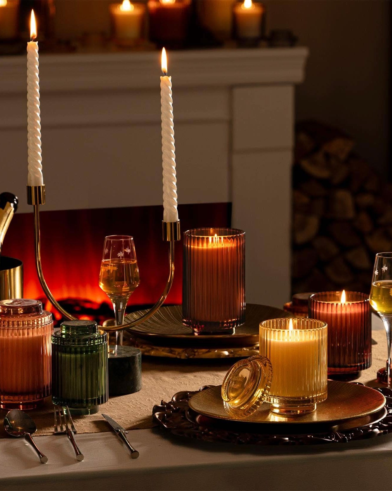 Candlelit table setting with wine glasses and candles in a cozy room.