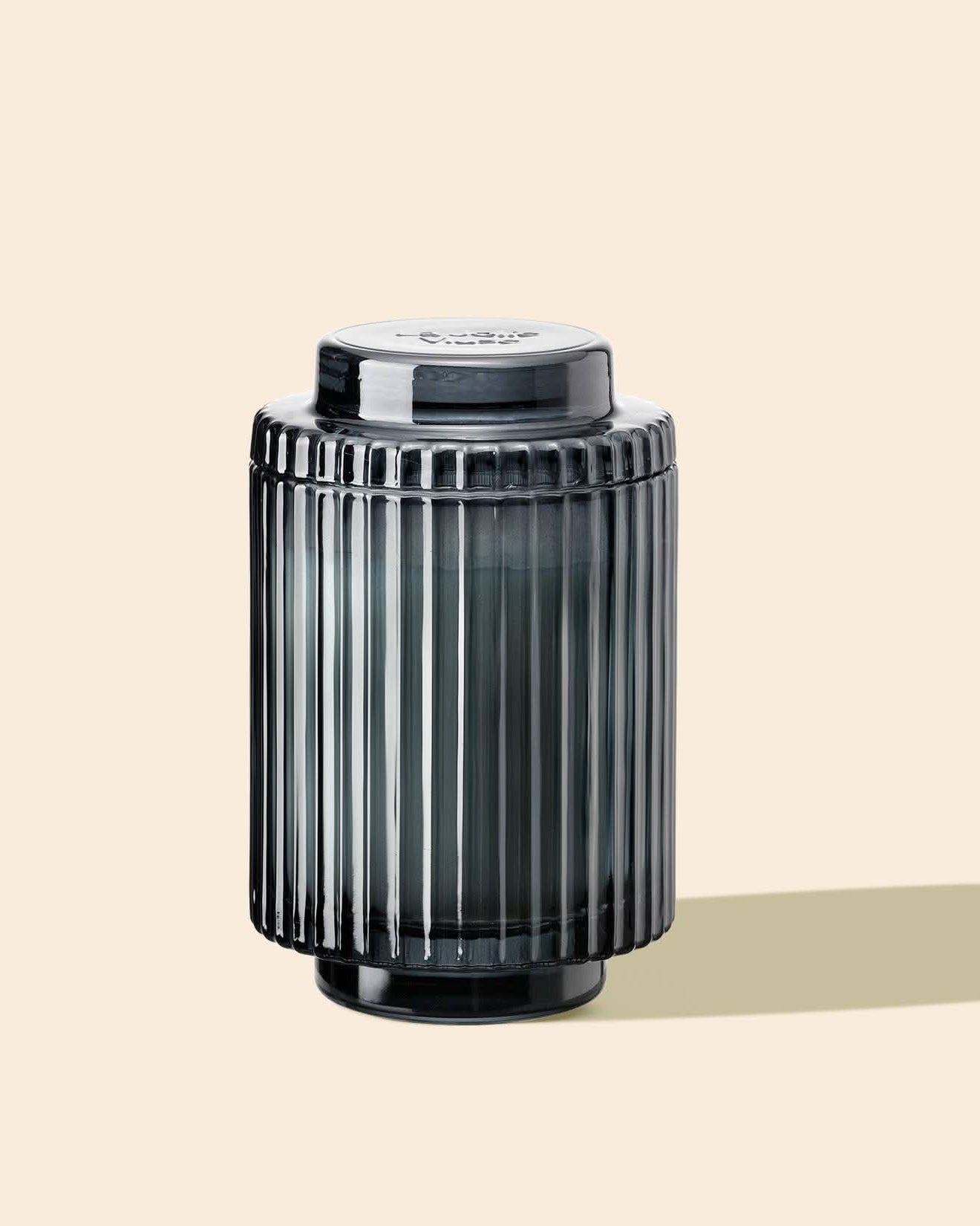 Dark gray cylindrical container with ribbed texture on a beige background