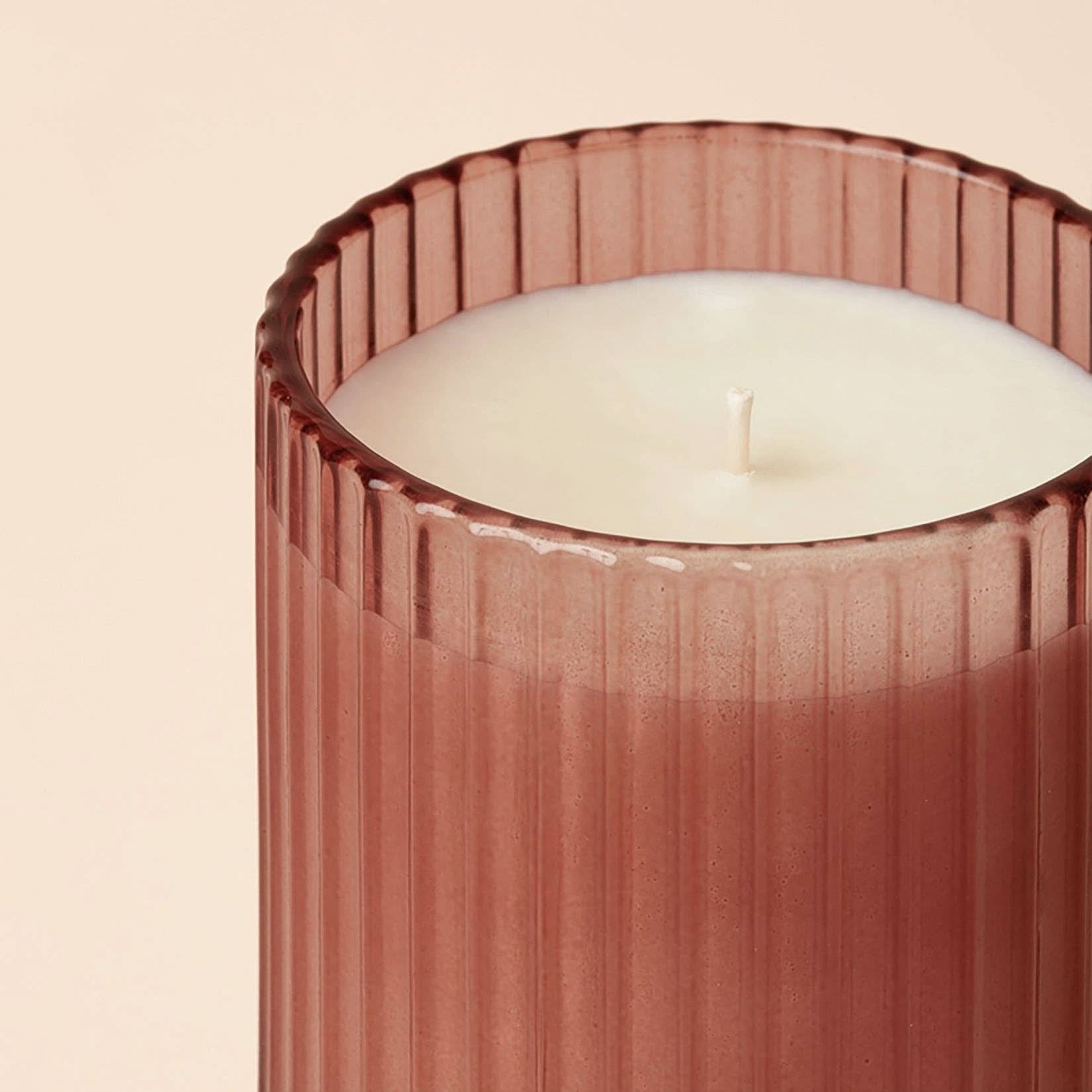 Candle in a ribbed pink holder on a beige background