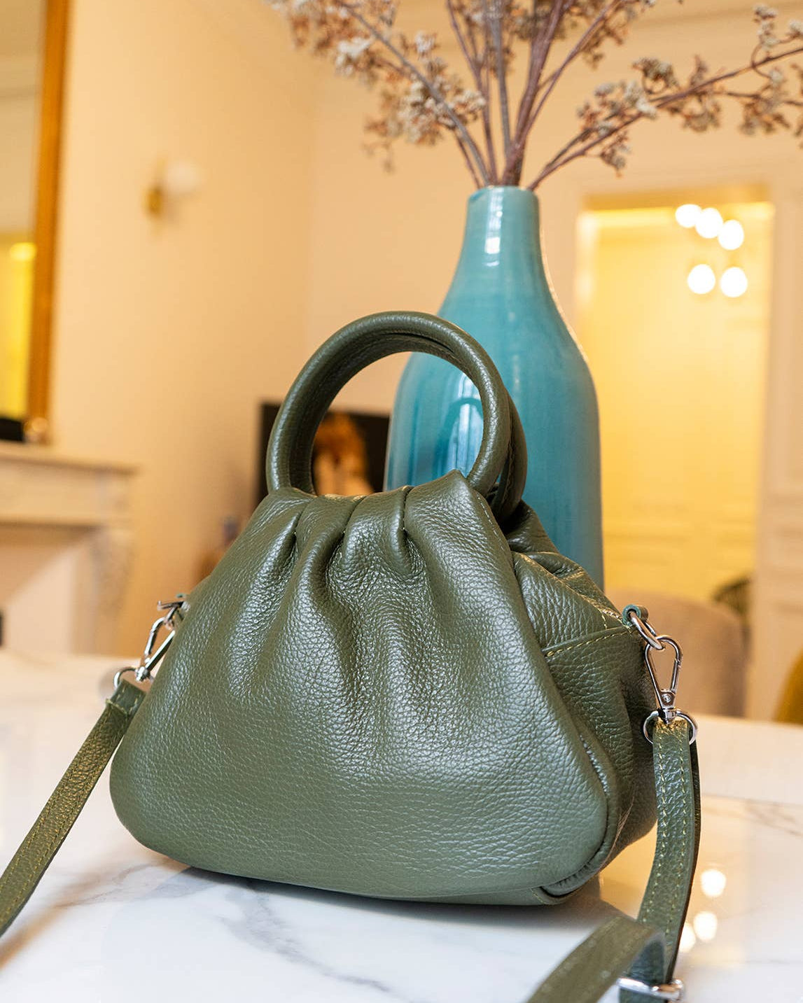Ayla Leather Green handbag on a white surface with a blurred background