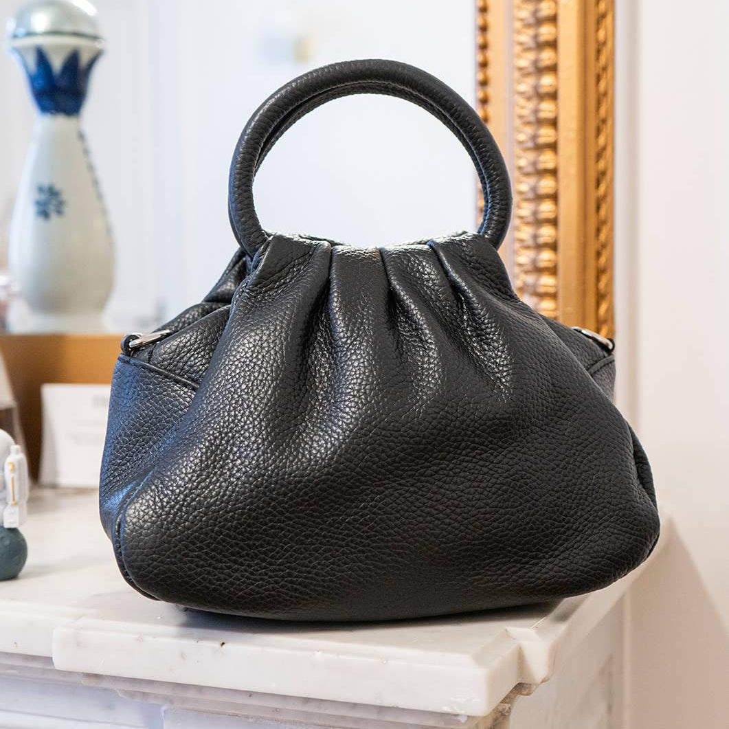 Black handbag on a decorative surface with a blurred background
