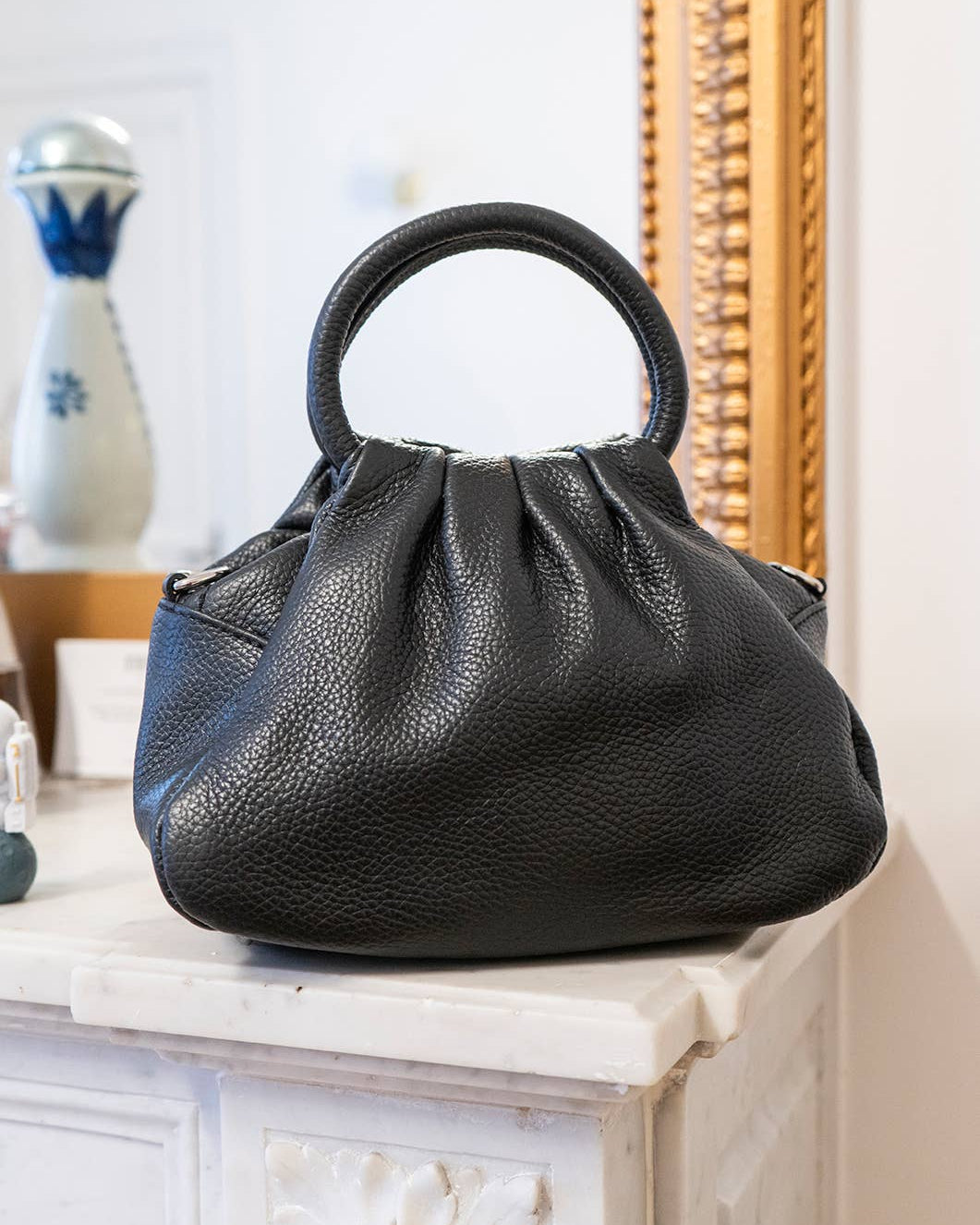 Black handbag on a decorative surface with a blurred background