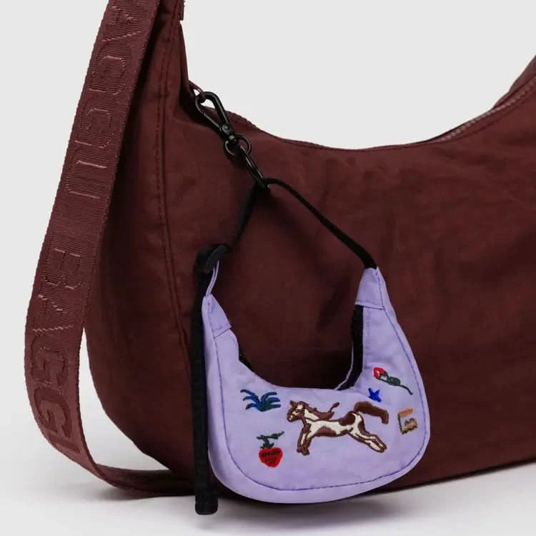 Purple embroidered crescent bag charm clipped on to a brown crescent baggu bag
