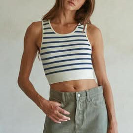 Woman wearing a white and light blue striped sleeveless U-V neckline tank top with a green mini skirt.