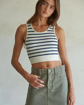 Woman wearing a white and light blue striped sleeveless U-V neckline tank top with a green mini skirt.