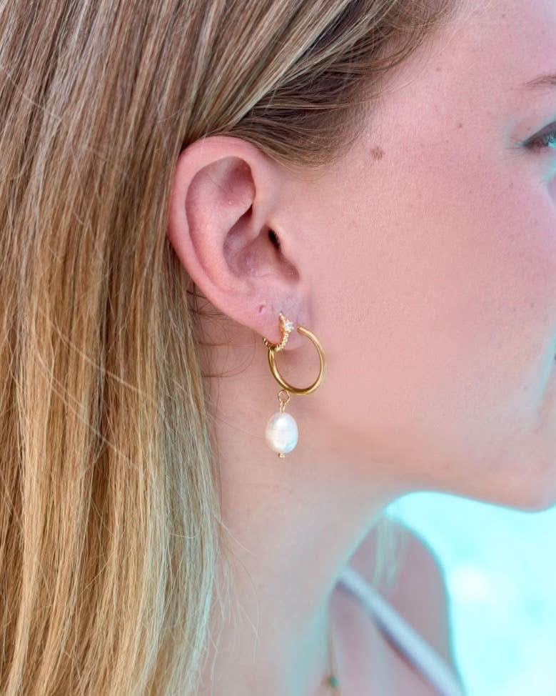 Woman wearing Waterproof gold huggie earrings with single Crystal gem in second piercing
