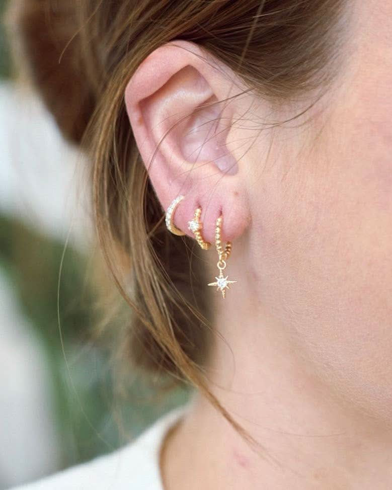Woman wearing Waterproof gold huggie earrings with single Crystal gem