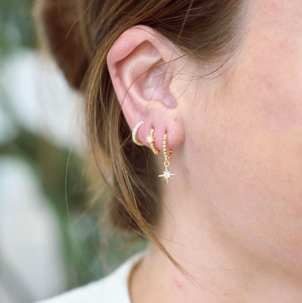 Woman wearing Waterproof gold huggie earrings with single Crystal gem