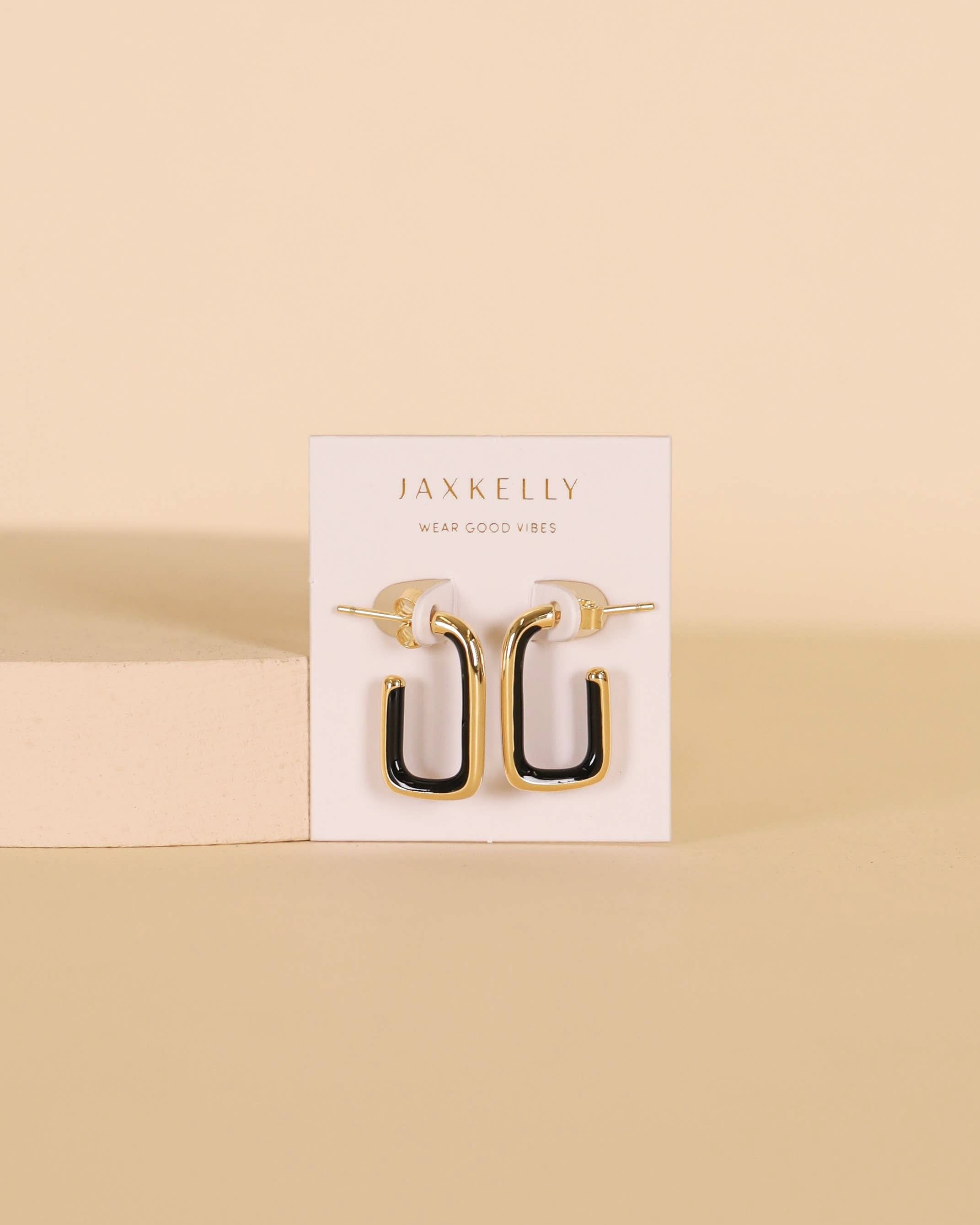 Gold and black earrings on a Jaxkelly branded card against a beige background