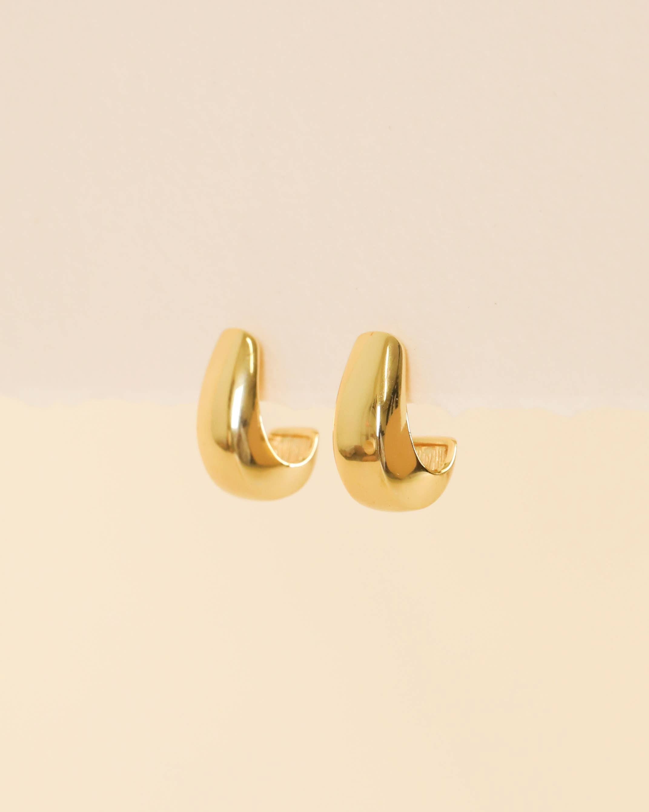 Bold Drop Gold Earrings hoop earrings on a beige background