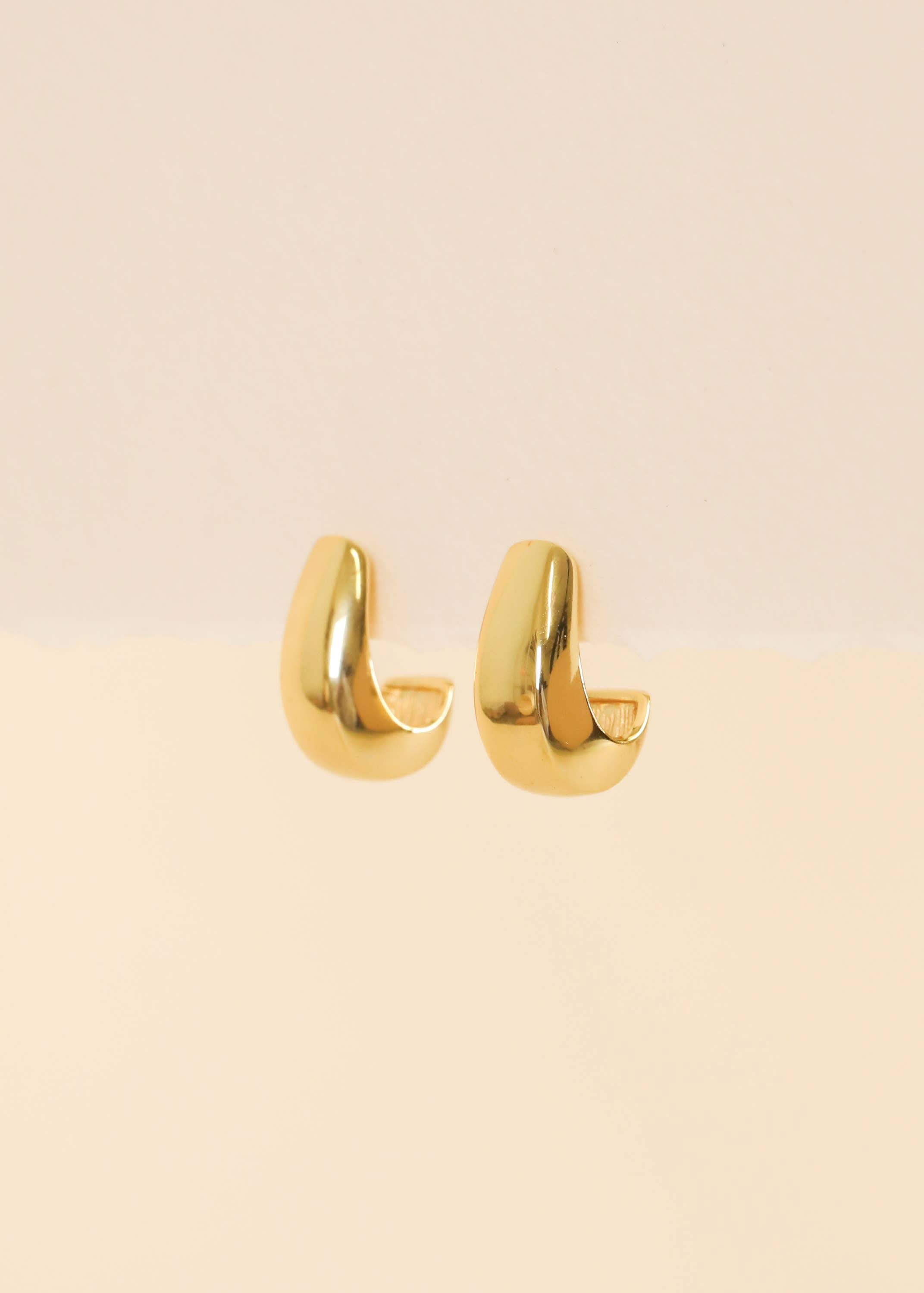 Bold Drop Gold Earrings hoop earrings on a beige background