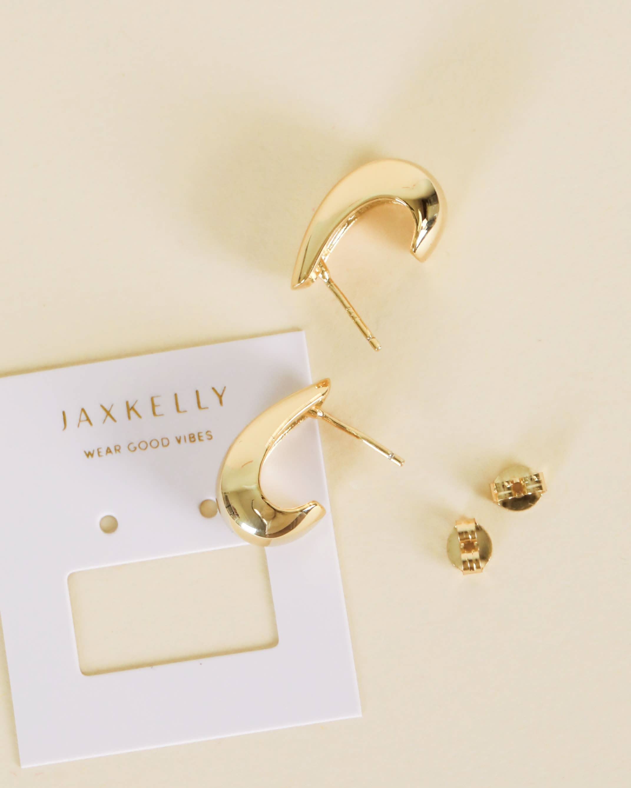 Gold hoop earrings on a beige card with 'JAXKELLY' branding