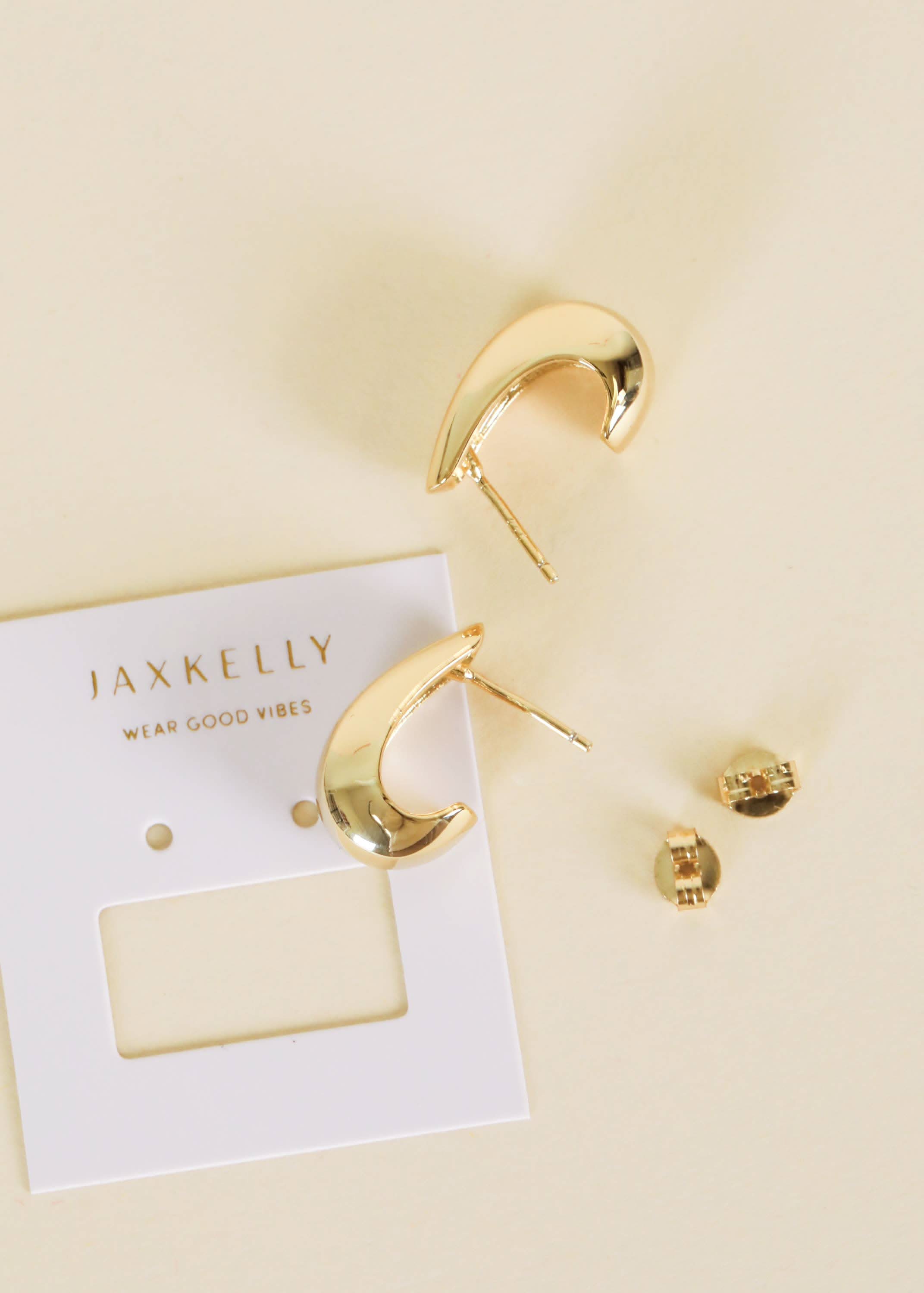 Gold hoop earrings on a beige card with 'JAXKELLY' branding