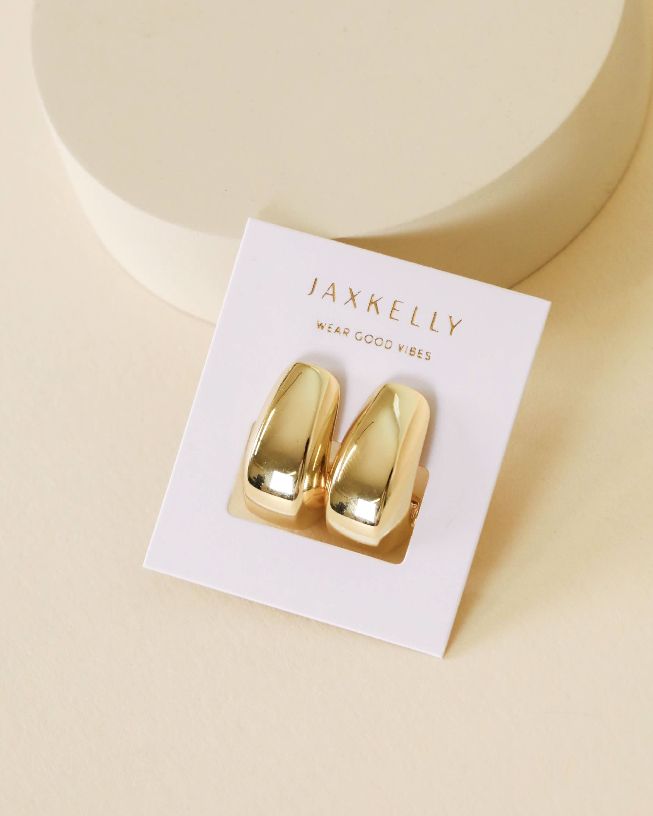Gold earrings on a JaxKelly branded card with a beige background