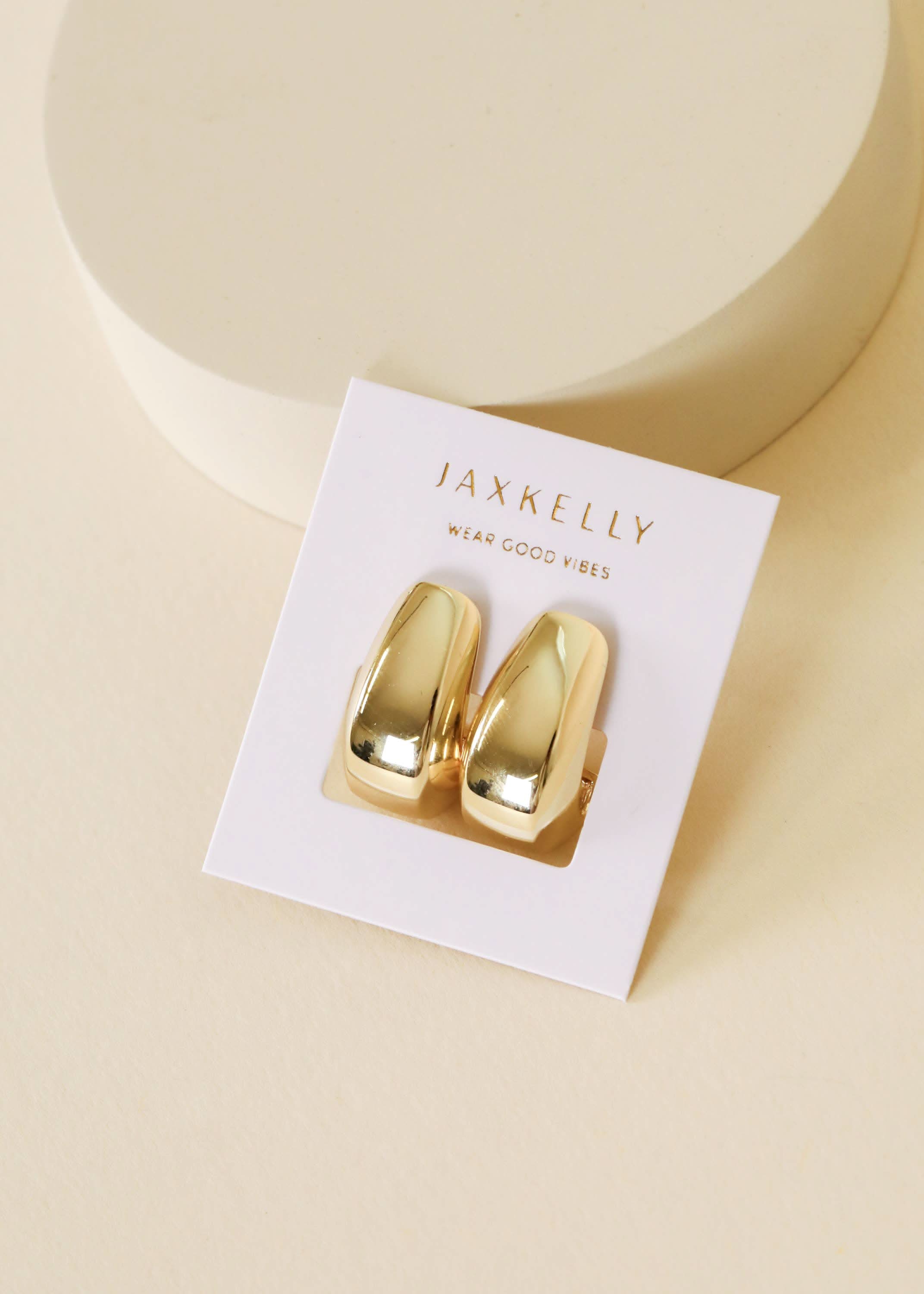 Gold earrings on a JaxKelly branded card with a beige background