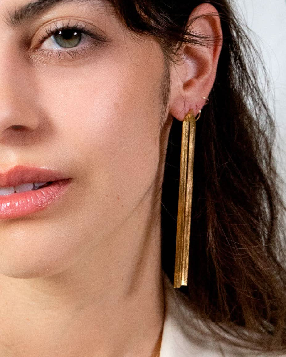 Close-up of a woman wearing gold earrings with a blurred background