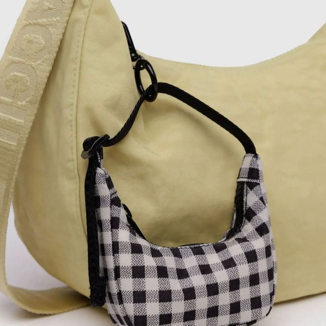Black and white gingham mini BAGGU bag charm clipped onto yellow normal sized BAGGU crescent bag