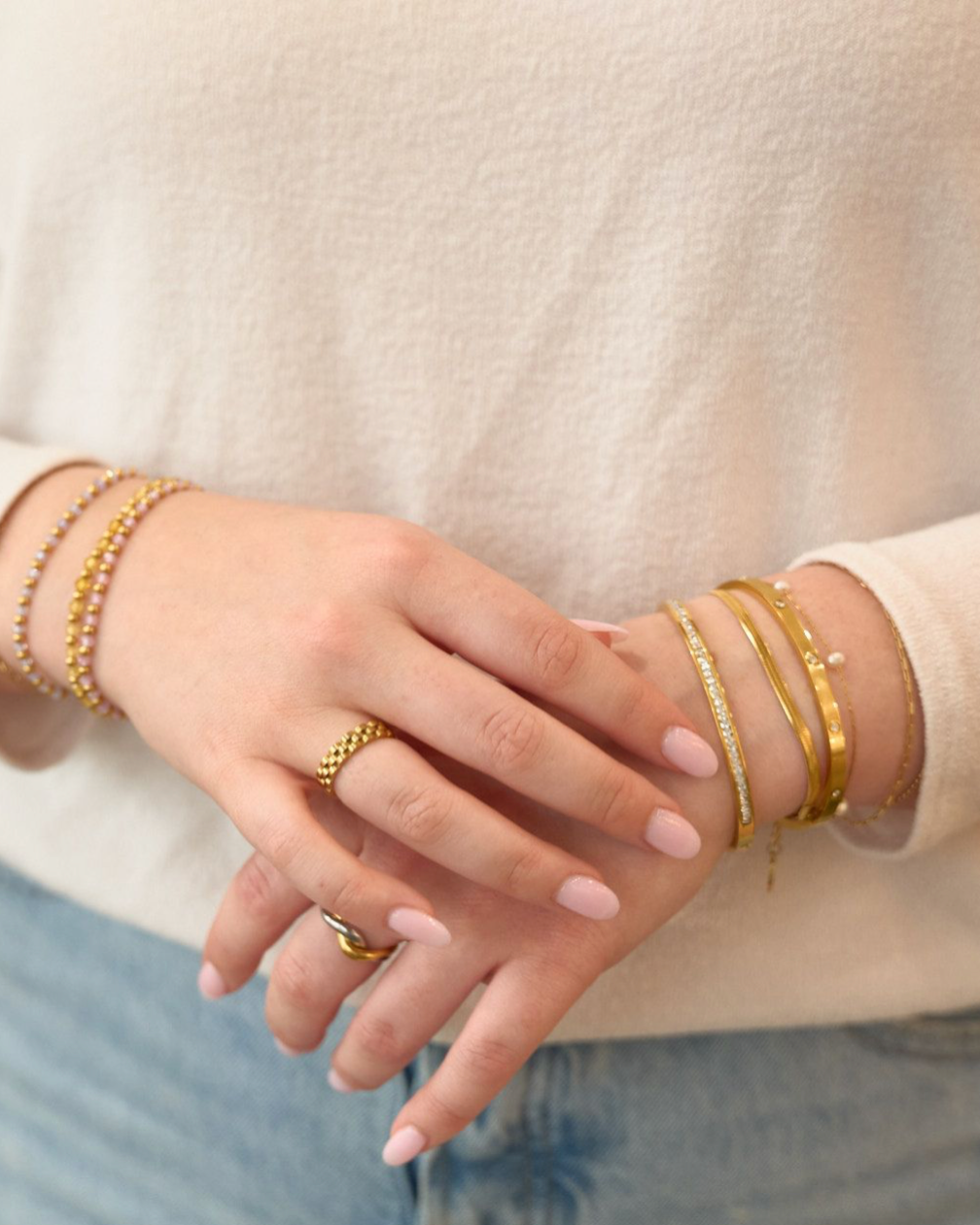 Woman wearing bracelets and rings including Gold