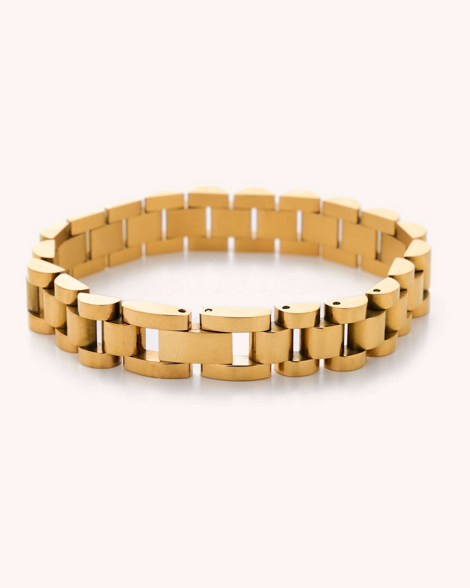 Gold watchband bracelet laying in a white background