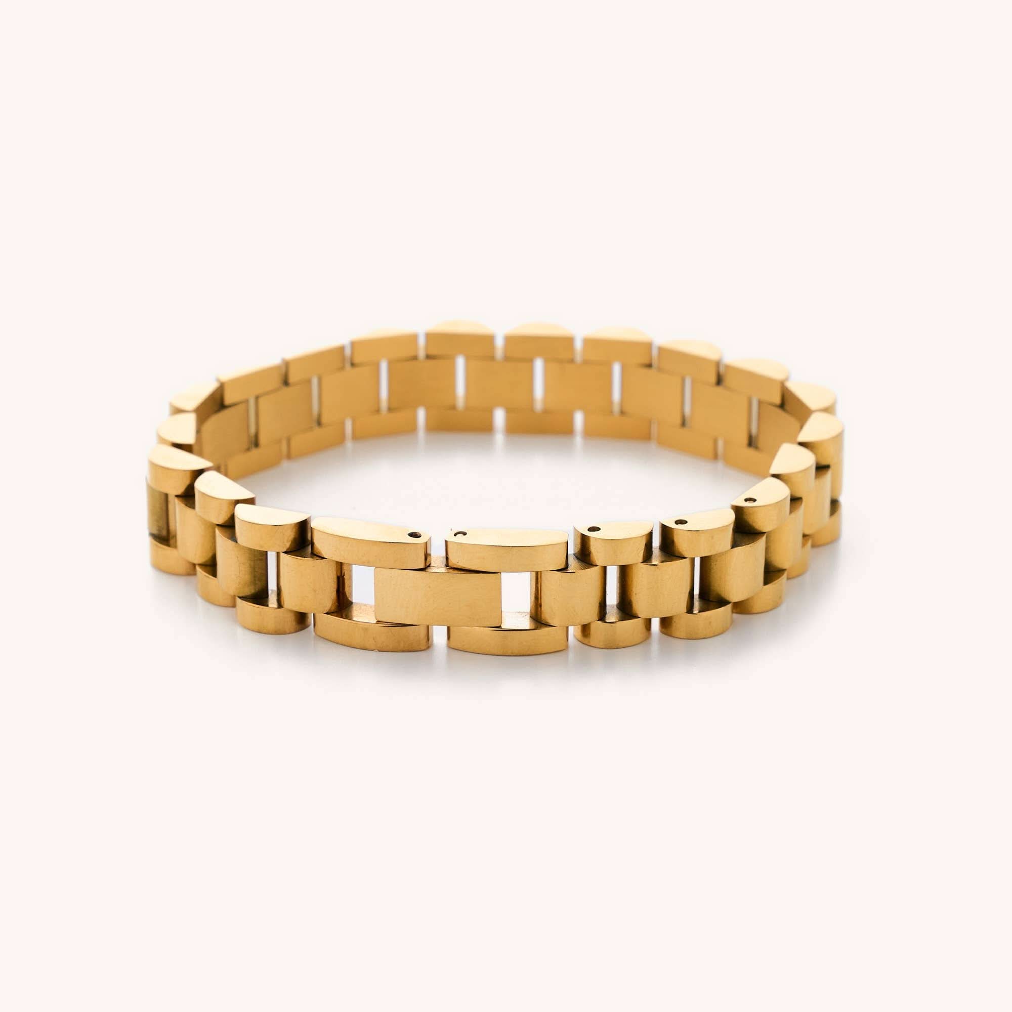 Gold watchband bracelet laying in a white background
