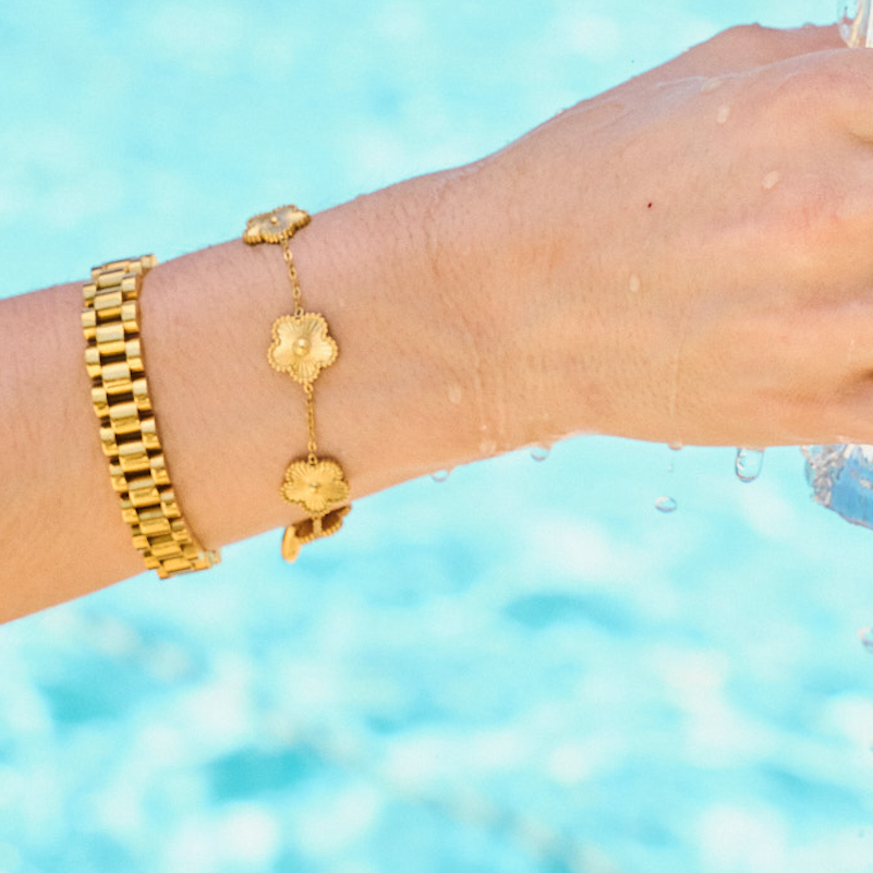 Woman wearing bracelet stack including gold watch band bracelet