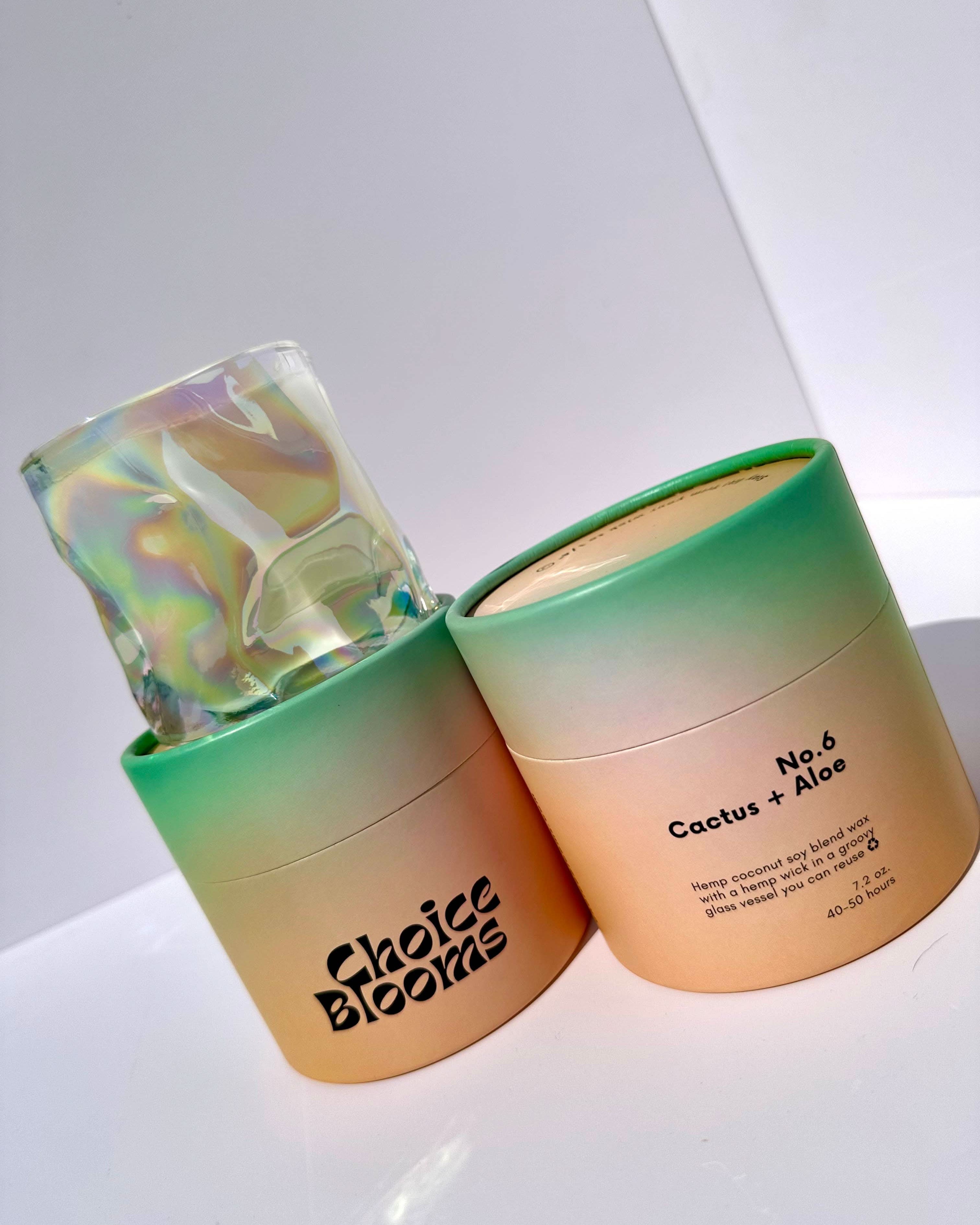 1 candle in a wavy glass with 2 green and orange candle packaging