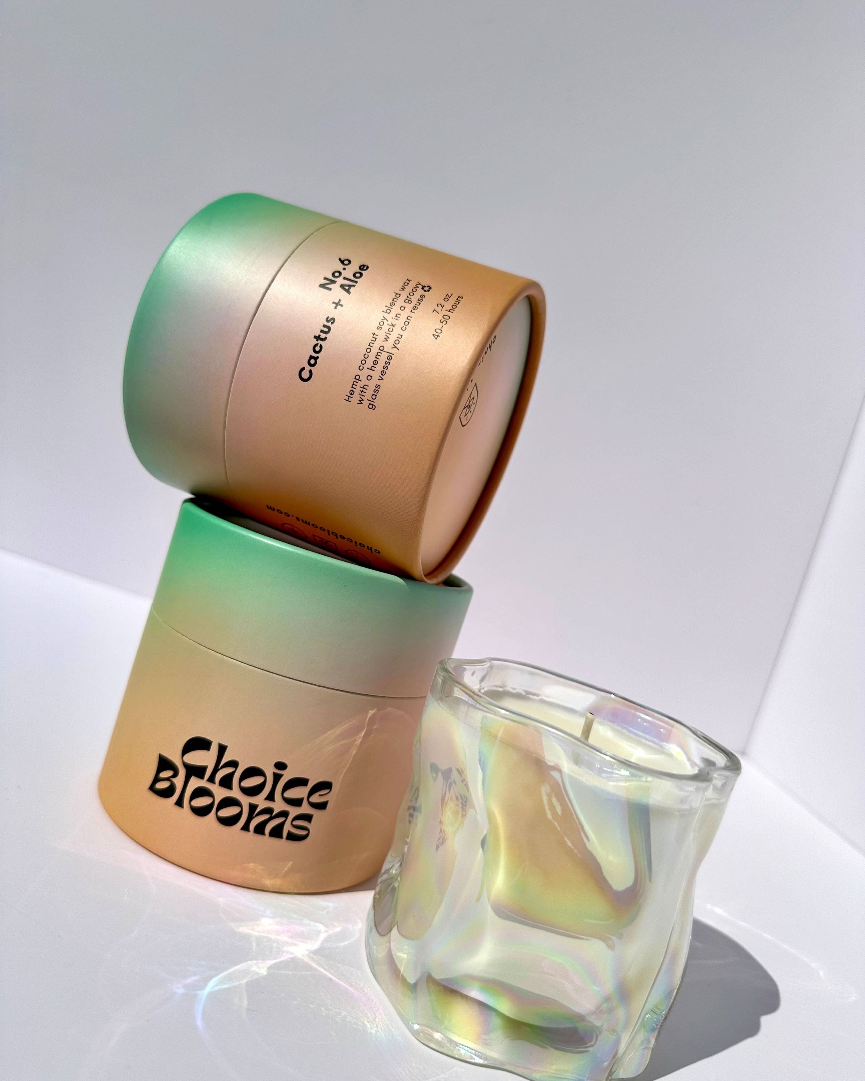 1 candle in a wavy glass with 2 green and orange candle packaging