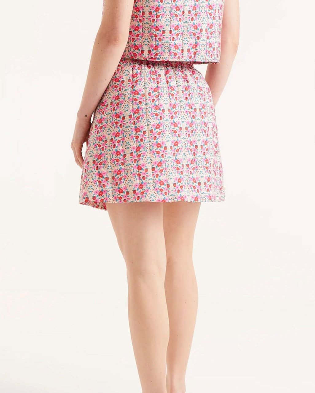 Woman wearing strawberry and floral collared ruffle sleeve button up skirt it's