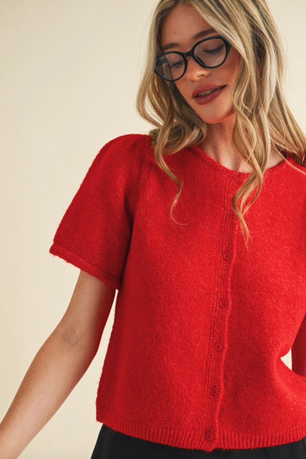 Woman wearing red, fuzzy, short sleeved, button up cardigan