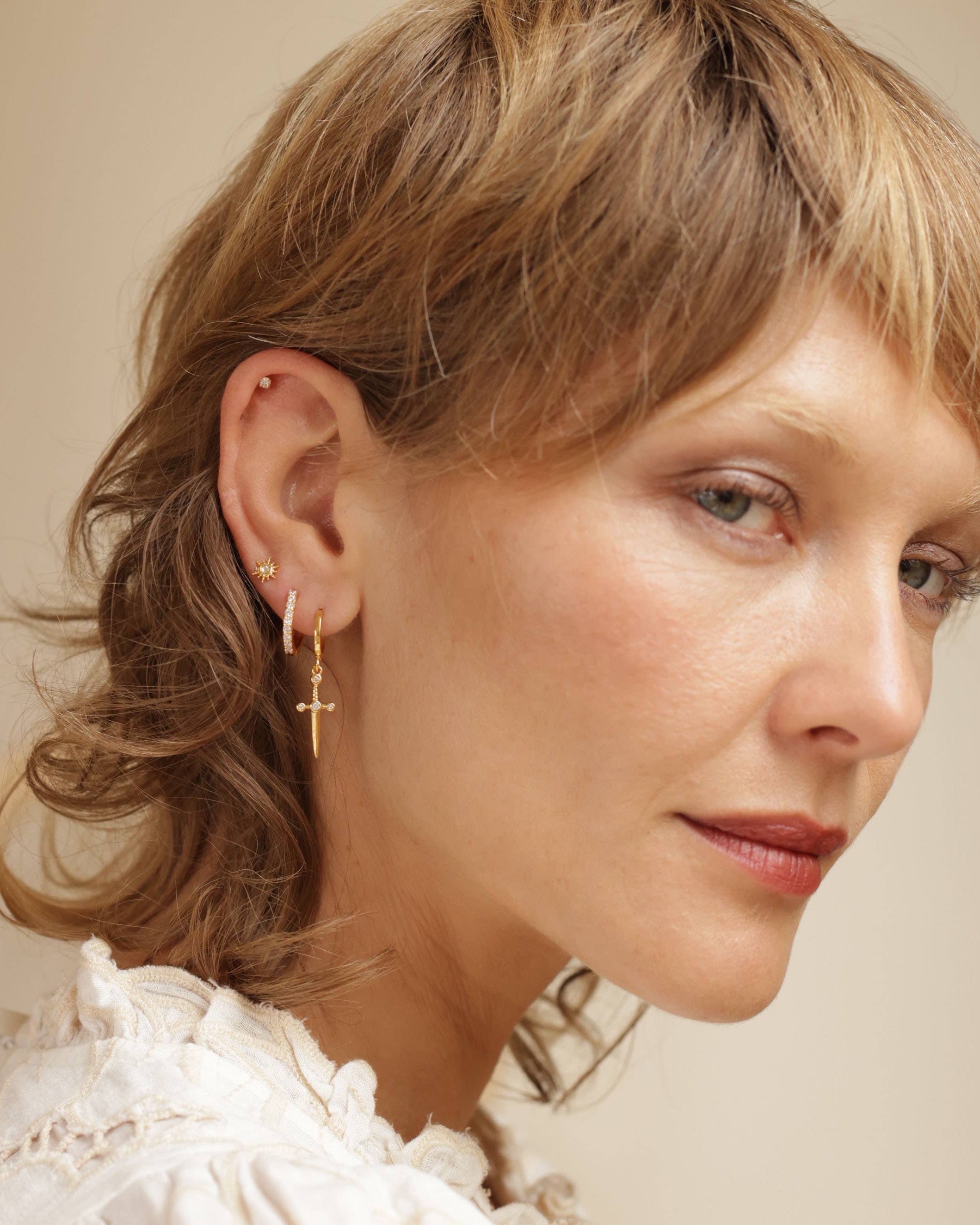 Close-up of a woman wearing gold earrings with a neutral glow