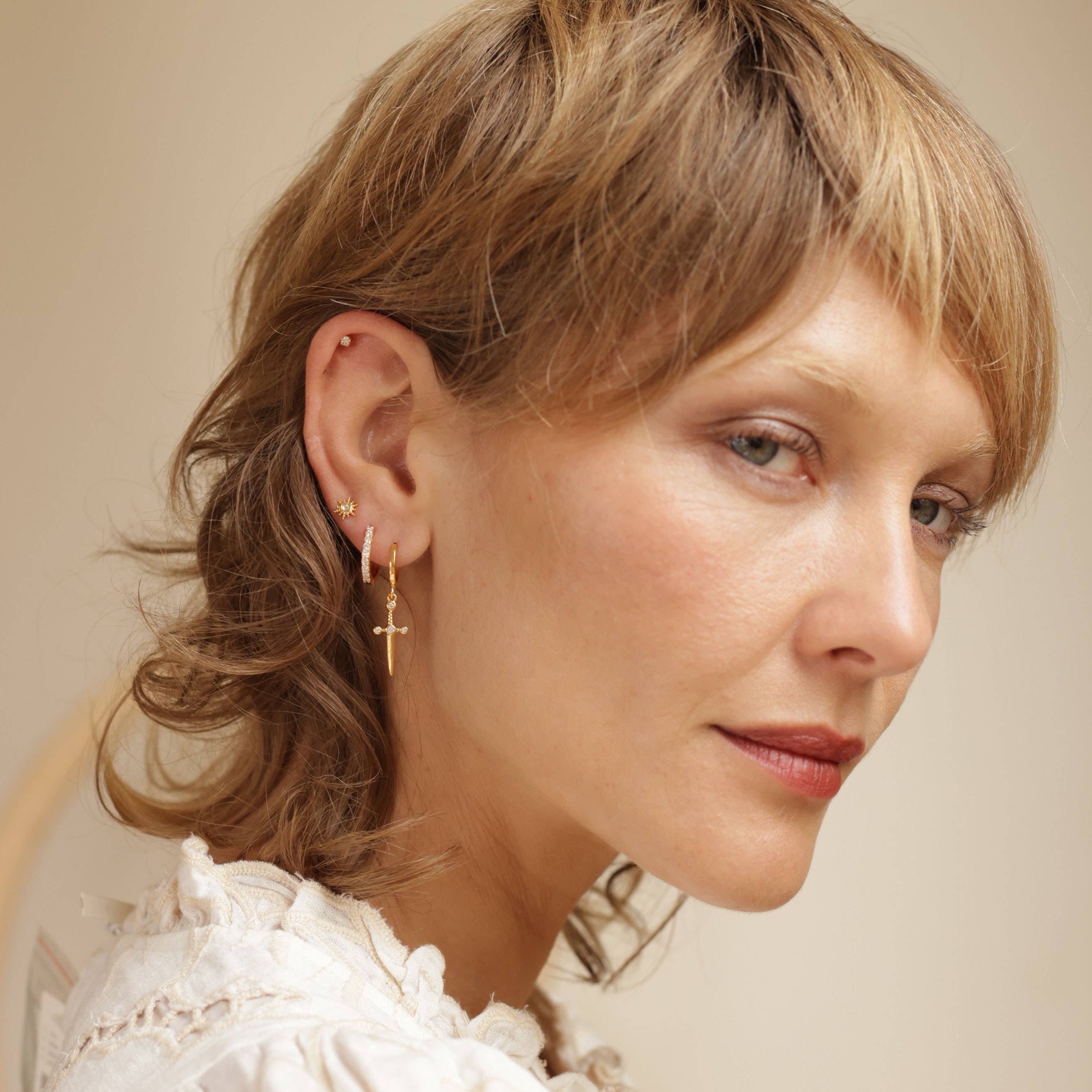 Close-up of a woman wearing gold earrings with a neutral glow