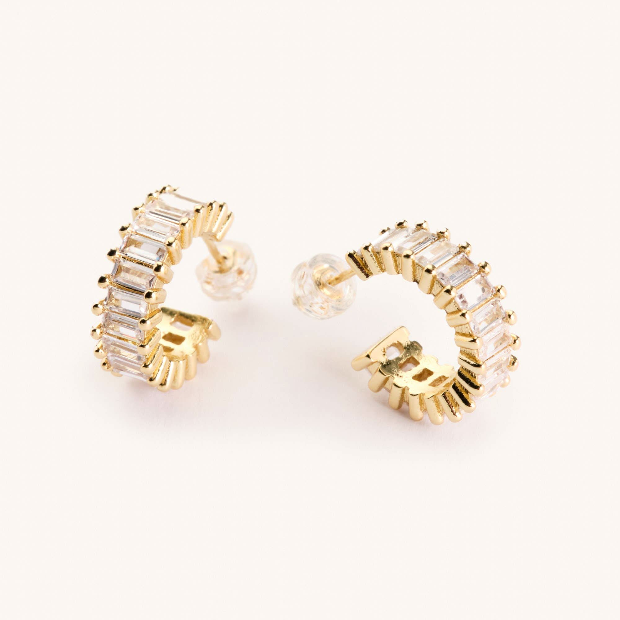 Gold diamond hoop earrings laying on a white background