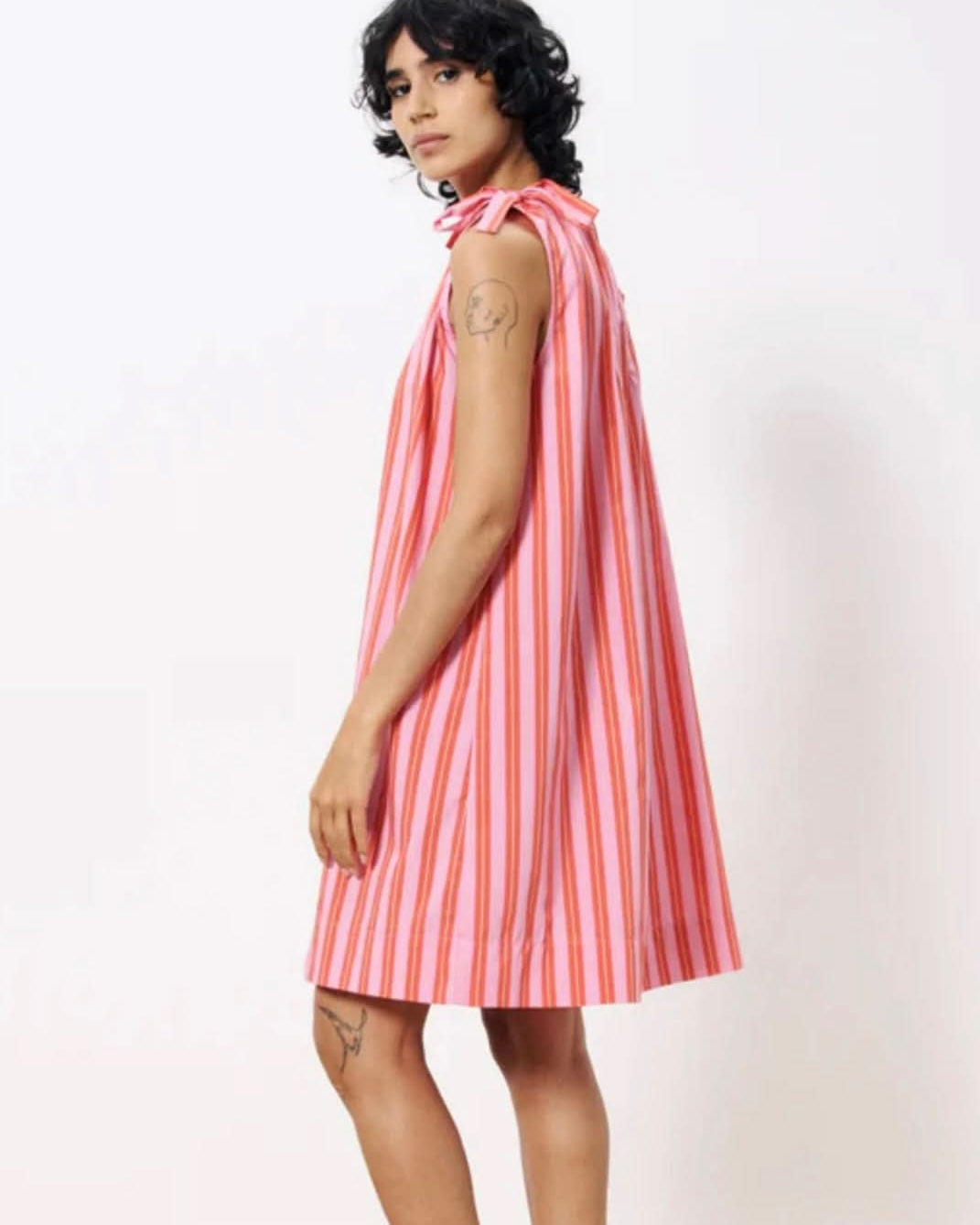 Woman wearing a pink and white striped dress against a plain background