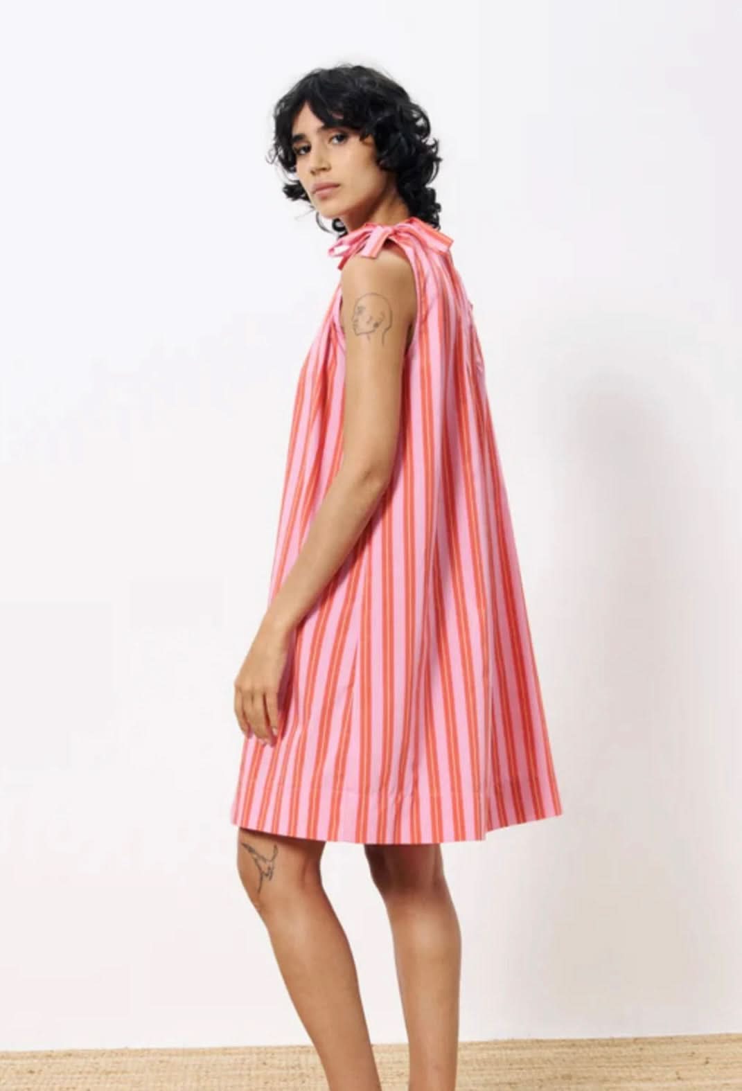 Woman wearing a pink and white striped dress against a plain background