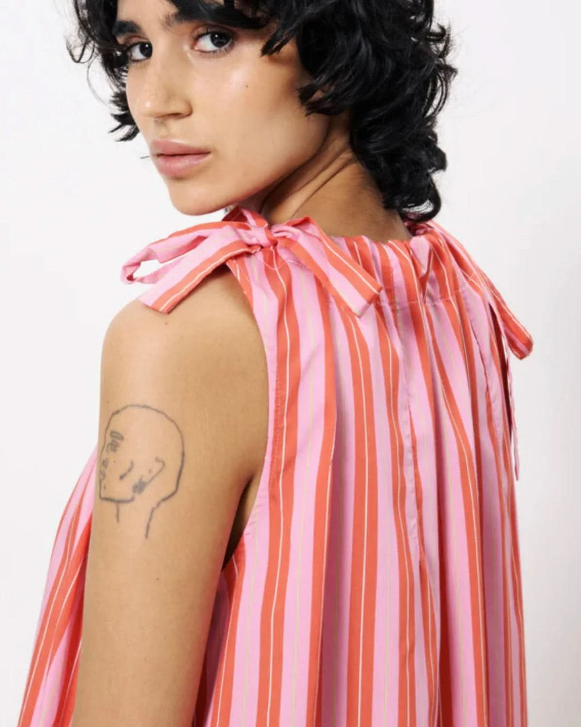 Person wearing a pink and orange striped sleeveless top on a white background