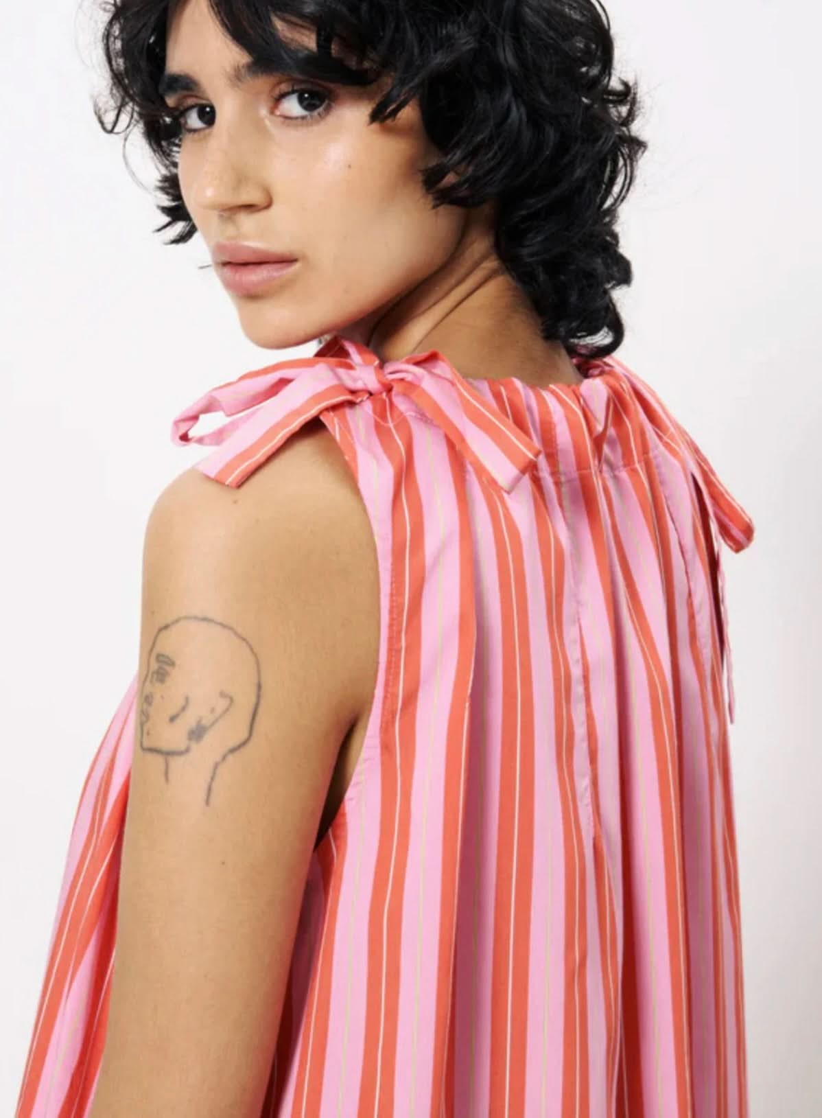 Person wearing a pink and orange striped sleeveless top on a white background