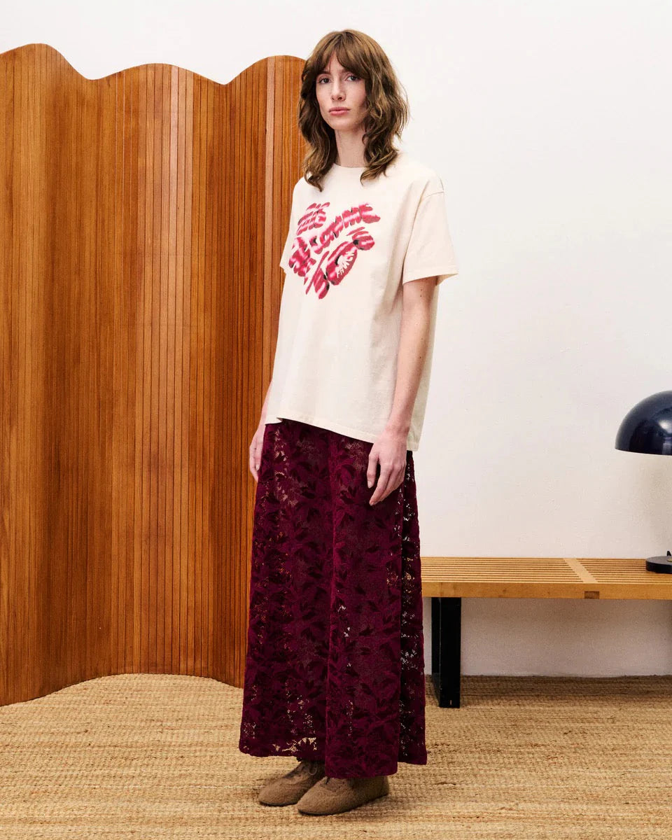 Woman wearing a dark red patterned skirt standing in a room.