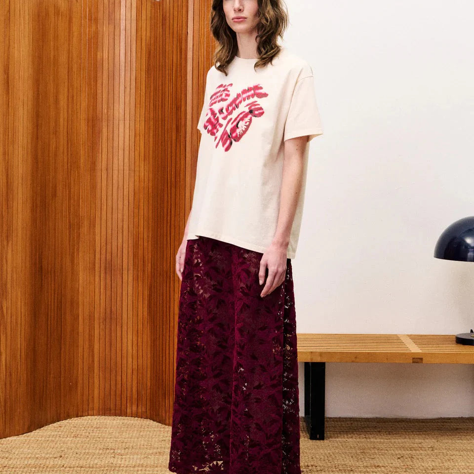 Woman wearing a dark red patterned skirt standing in a room.