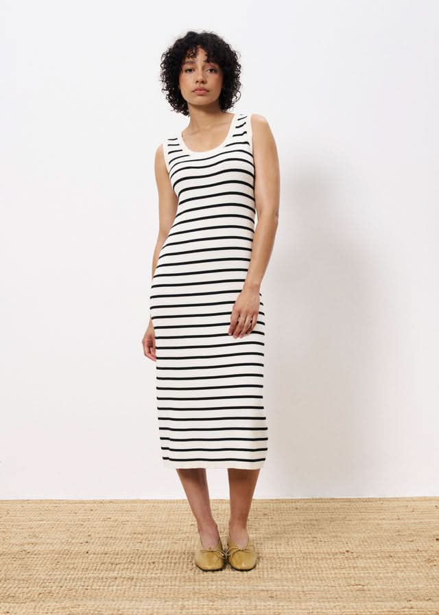Woman wearing a black and white striped dress against a plain background