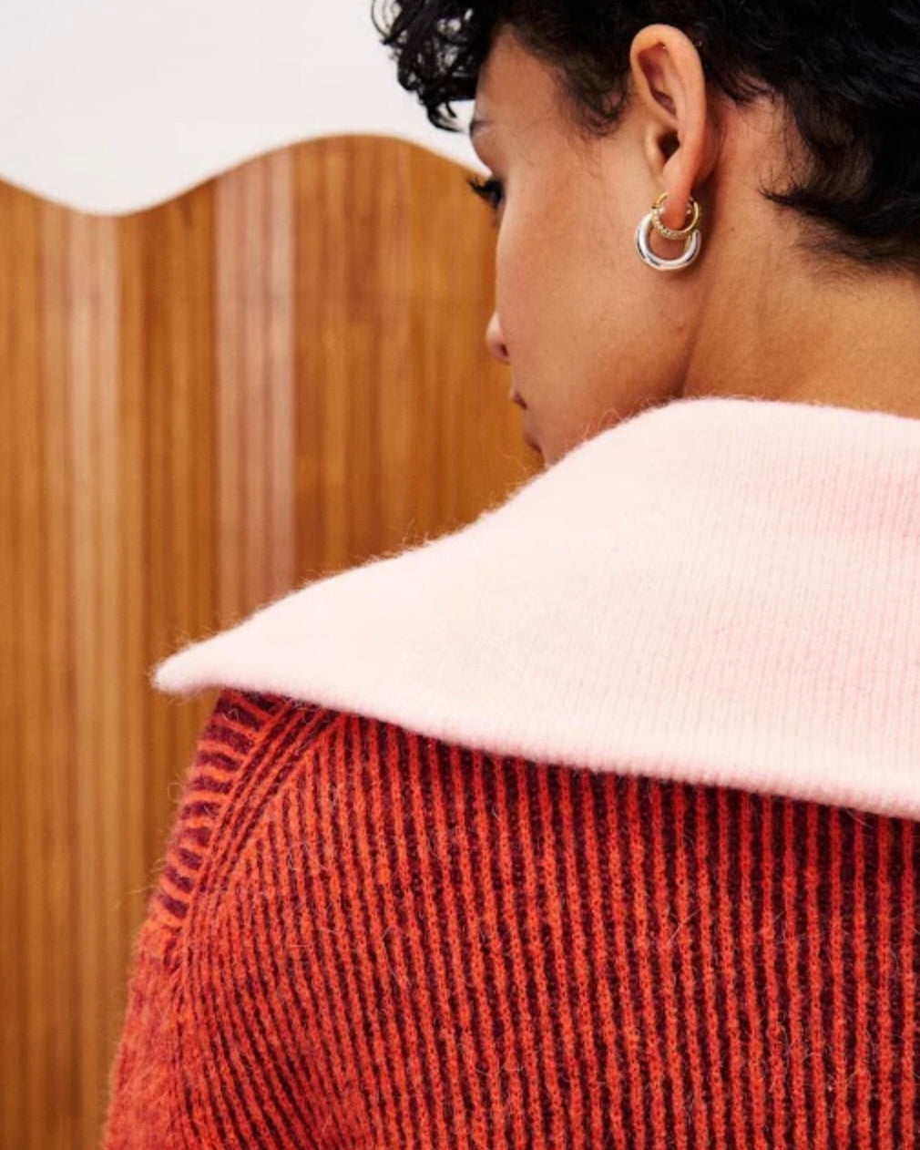 Person wearing a red textured sweater with a white collar.